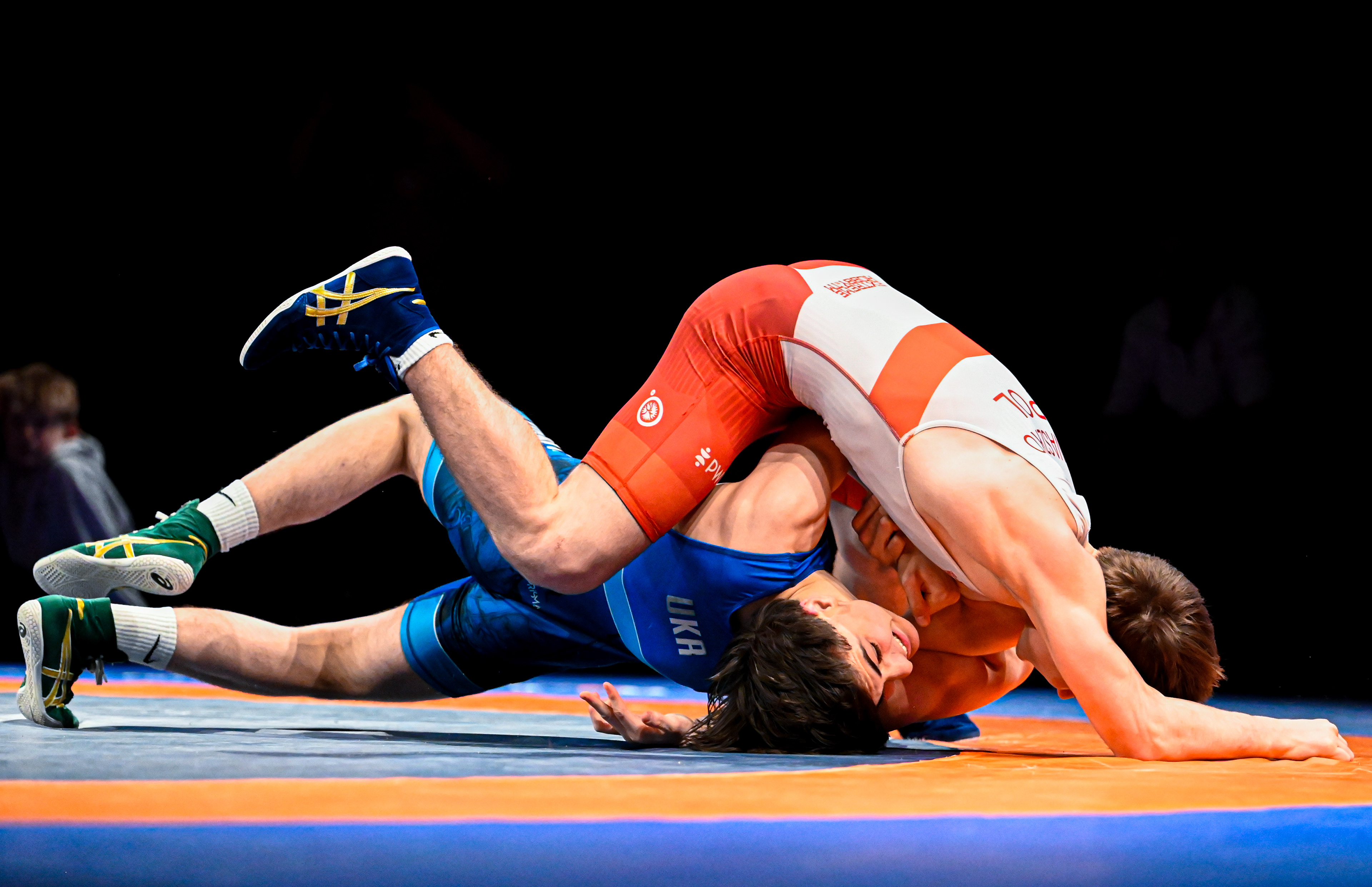 Two male youth wrestlers compete in a freestyle wrestling match at Frem Cup 2026 in Randers, Denmark, with the athlete in red executing a dominant pinning hold on his opponent on the mat during an international tournament bout.