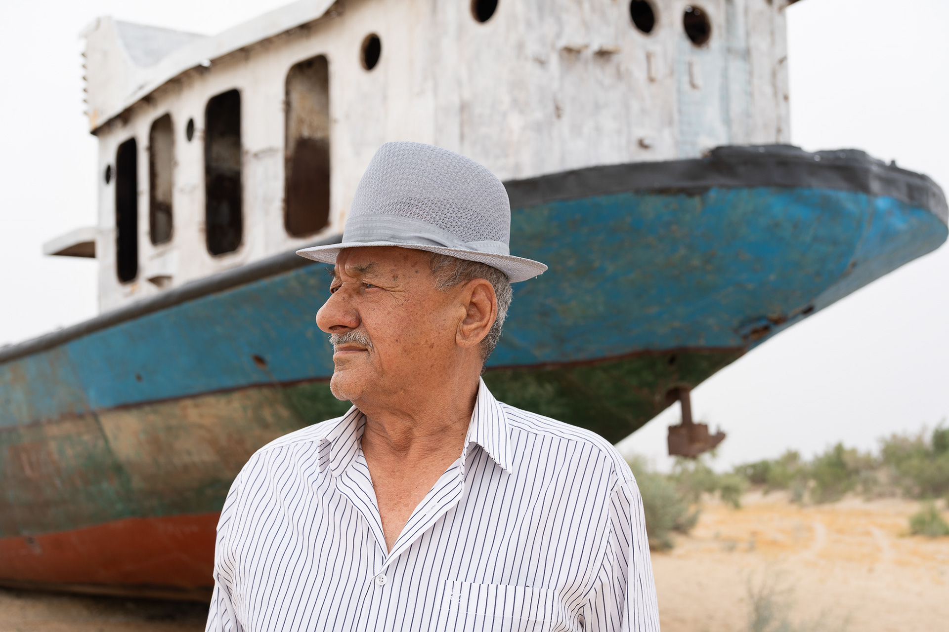 Ametov Kalbay, ancien pêcheur, pose devant un navire échoué