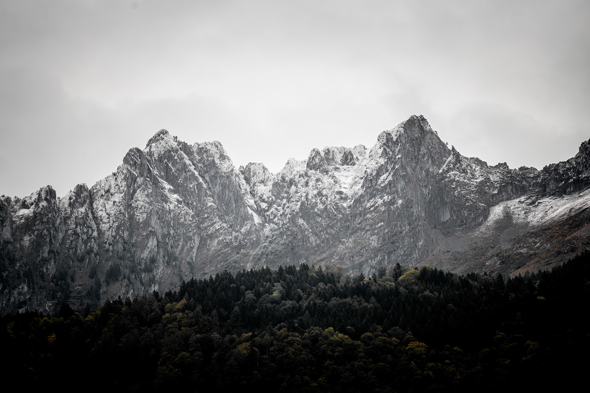 Schroffe Bergspitzen mit Schnee und herbstlichem Wald