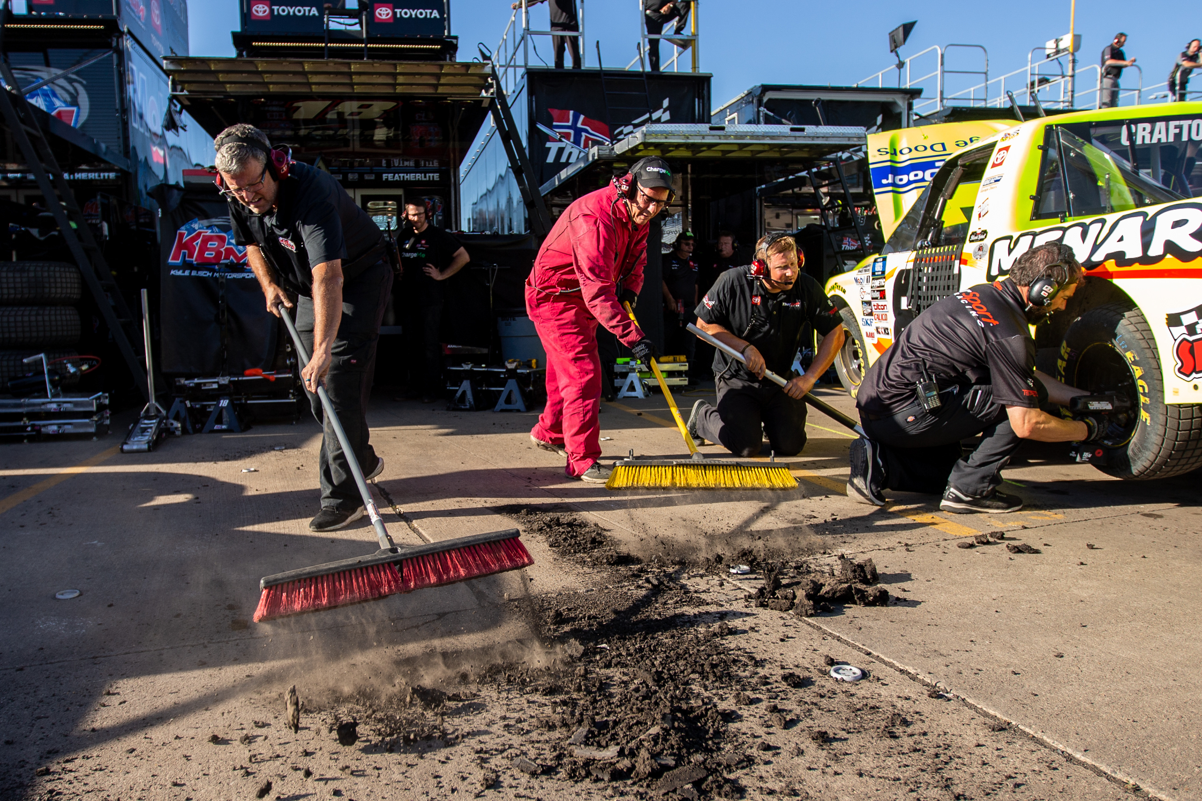 Crew members clear excess dirt debris from their pit stall during a practice session for the Clean Harbors 150 NASCAR Camping World Truck Series Race at Knoxville Raceway in Knoxville, Iowa on Friday, June 17, 2022.