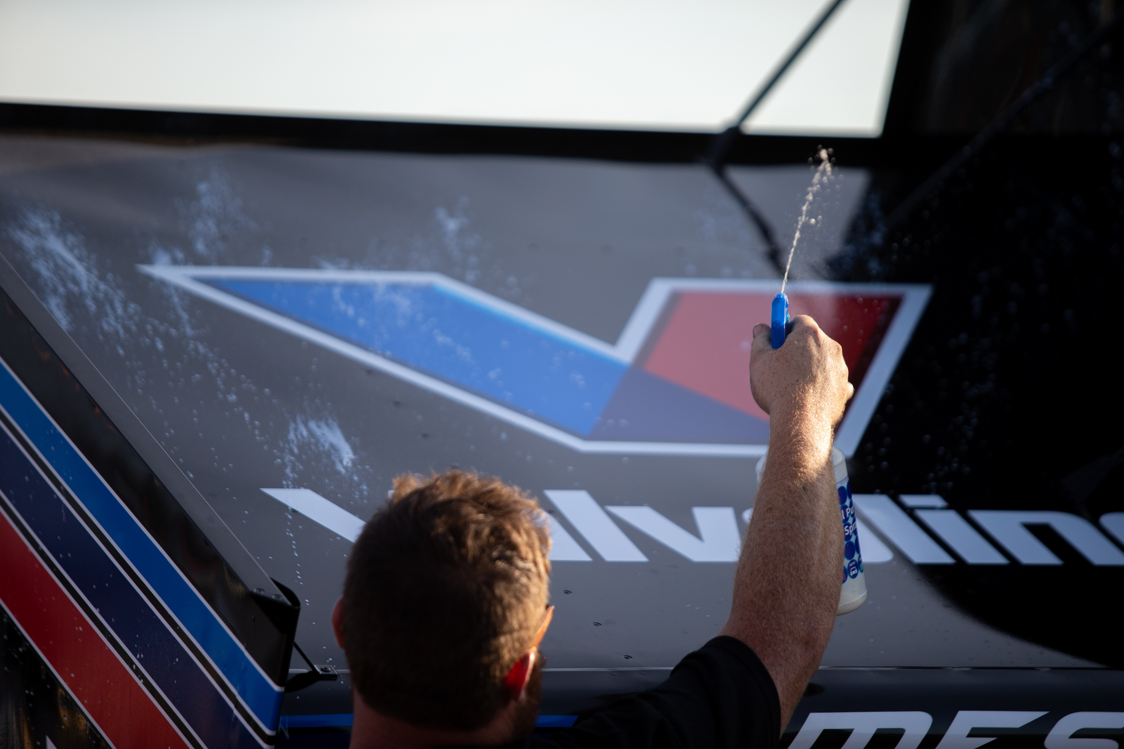 A crew member sprays down a car during FVP Friday Hard Knox Prelim Night of the 60th Annual NOS Energy Drink Knoxville Nationals presented by Caseys at Knoxville Raceway in Knoxville, Iowa on Friday, Aug. 13, 2021.