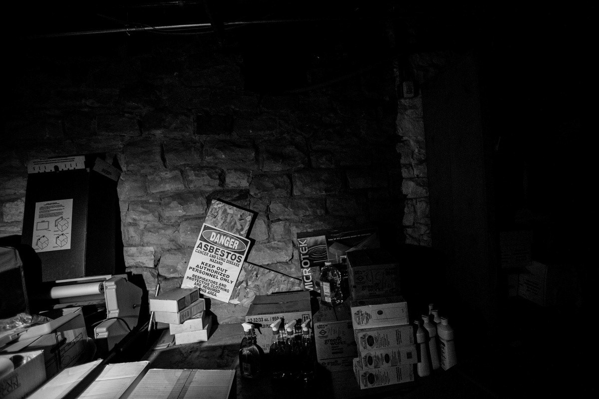 Asbestos warning sign in basement storage.