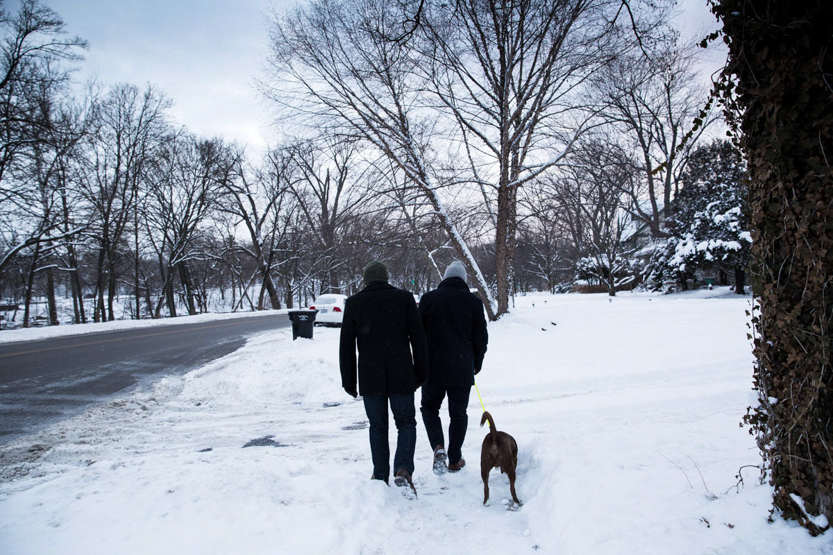 Mayor Pete Buttigieg alonside Chasten walking along snow covered sidewalk