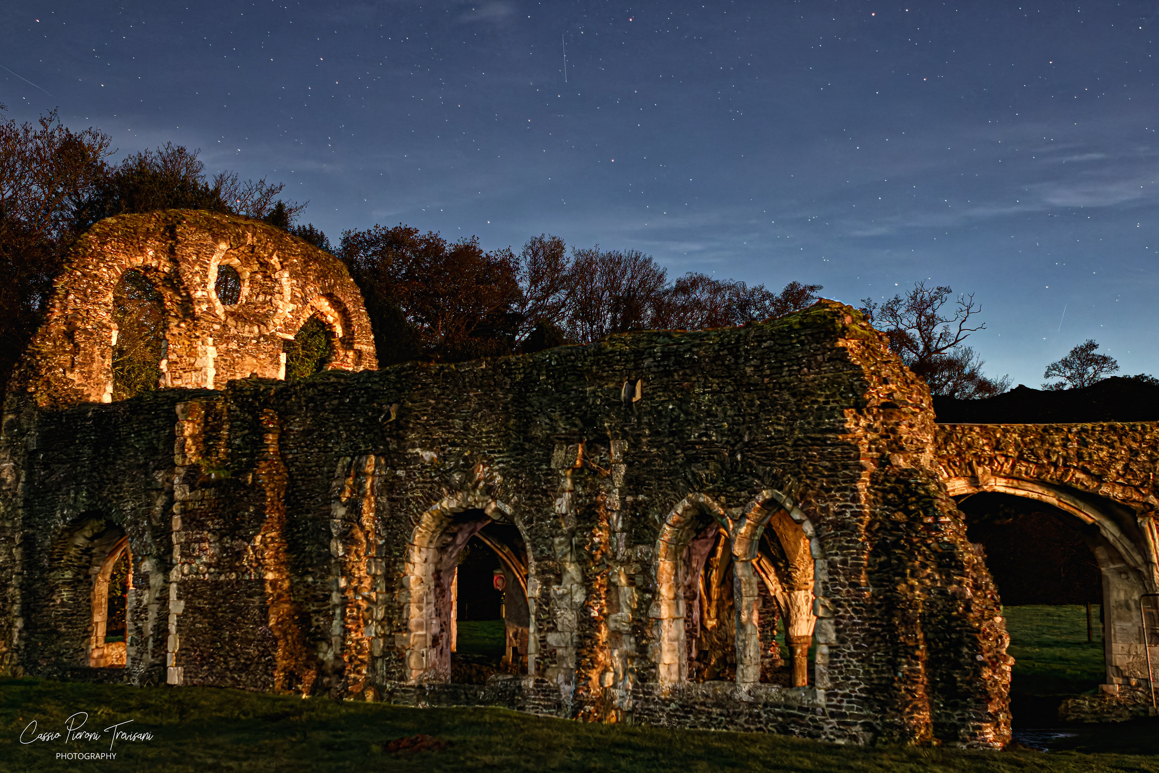 Night photo of Waverley Abbey ruins illuminated under a starry sky.
