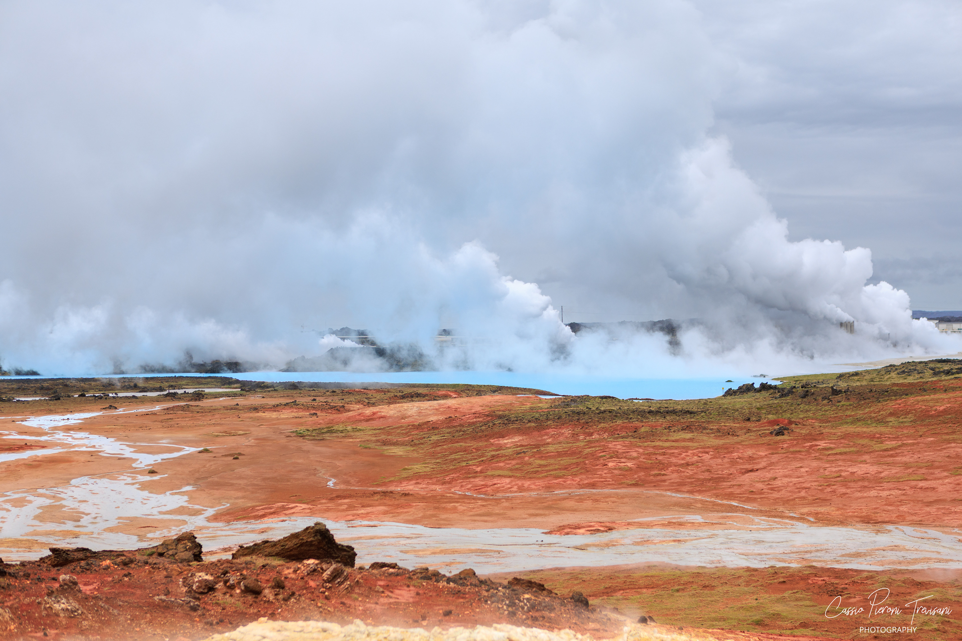 Steam rolls across milky-blue geothermal water and red mineral earth, revealing the intense heat beneath the Reykjanes landscape.