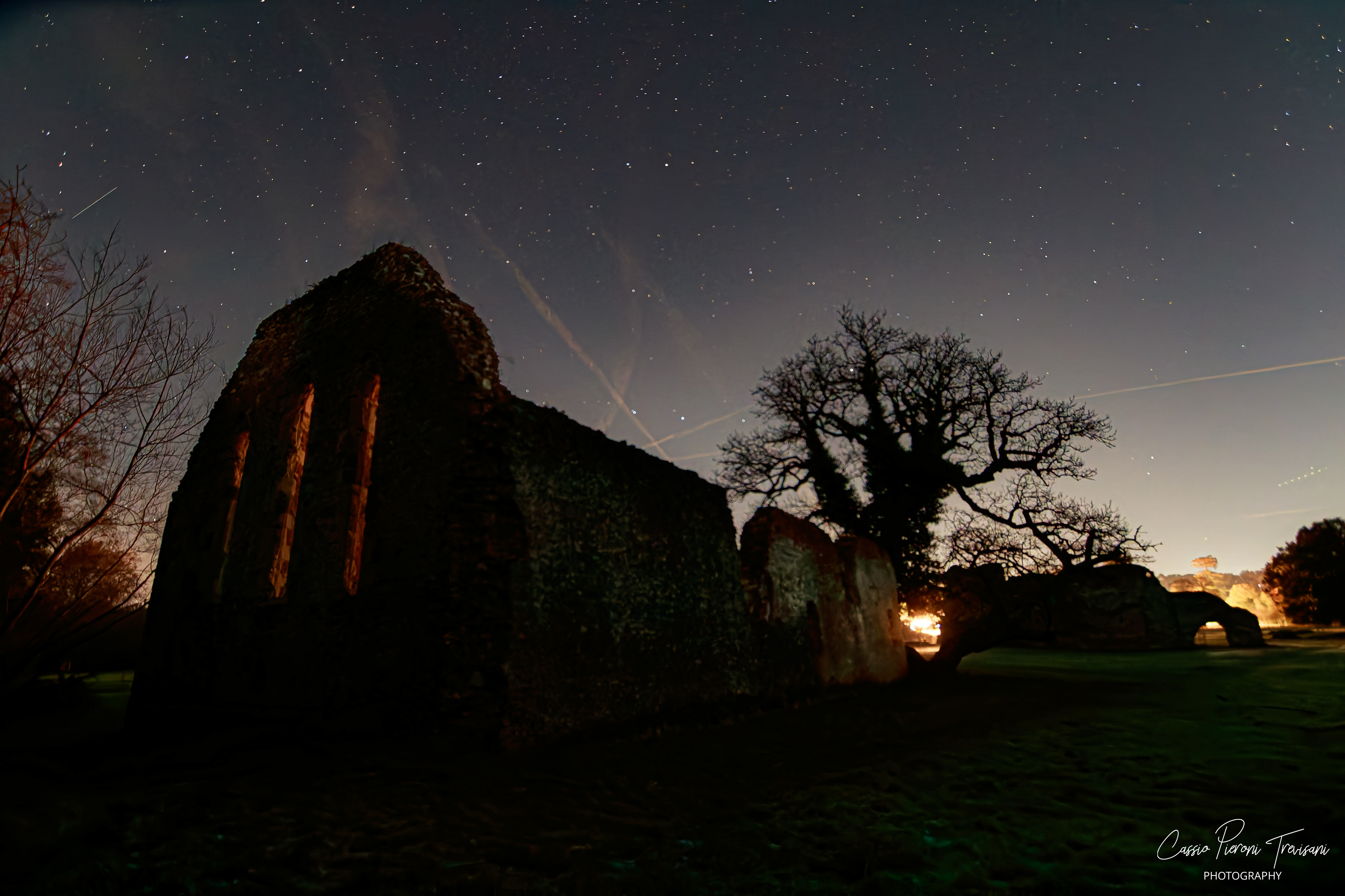 Silhouetted Waverley Abbey building with star trails and nighttime sky glow.