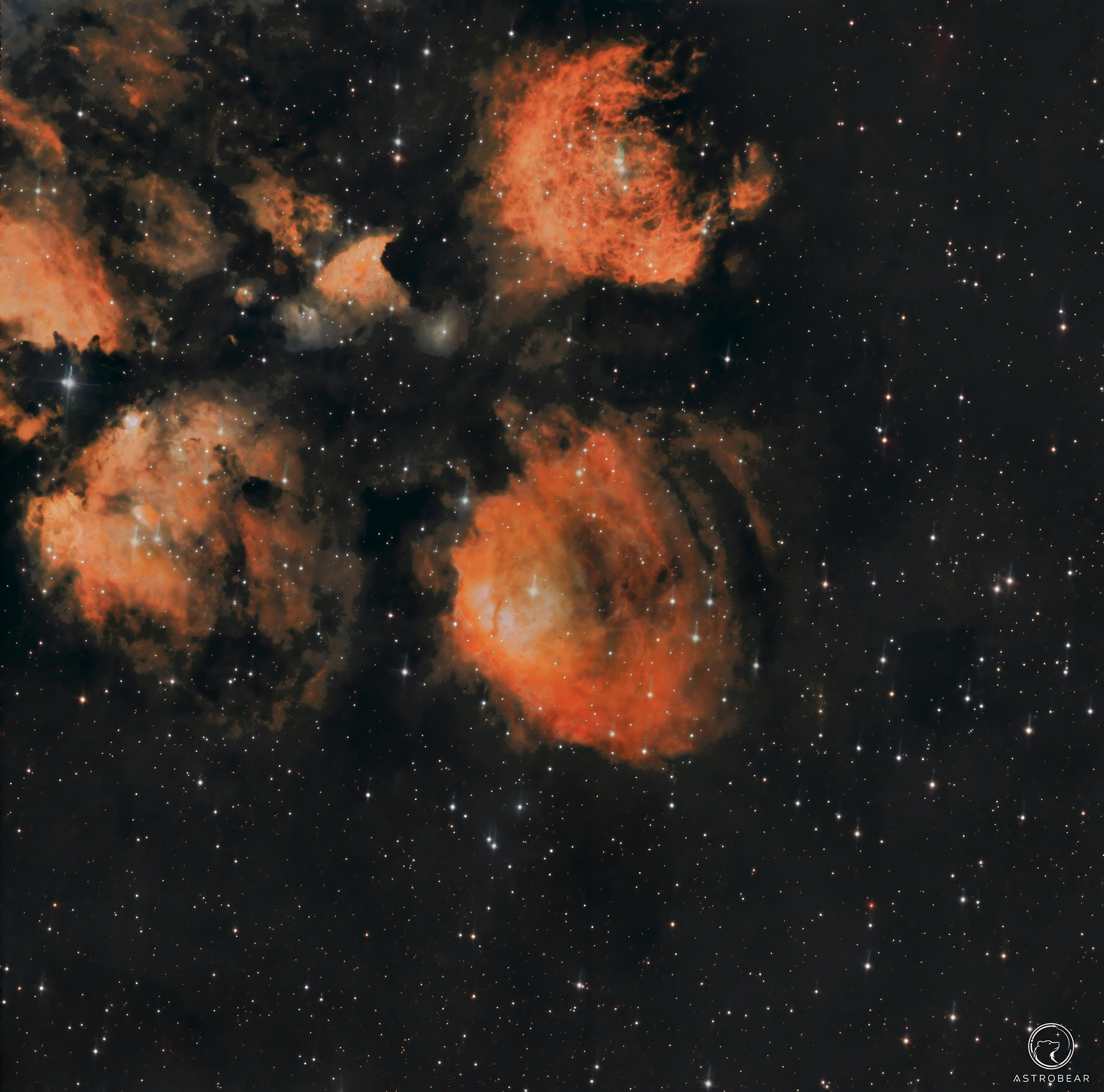 A deep-sky image of NGC 6334, the Cat’s Paw Nebula. Several large orange-red emission nebula regions appear across the left and centre of the frame, surrounded by dark dust lanes and a dense field of white stars against a black background.