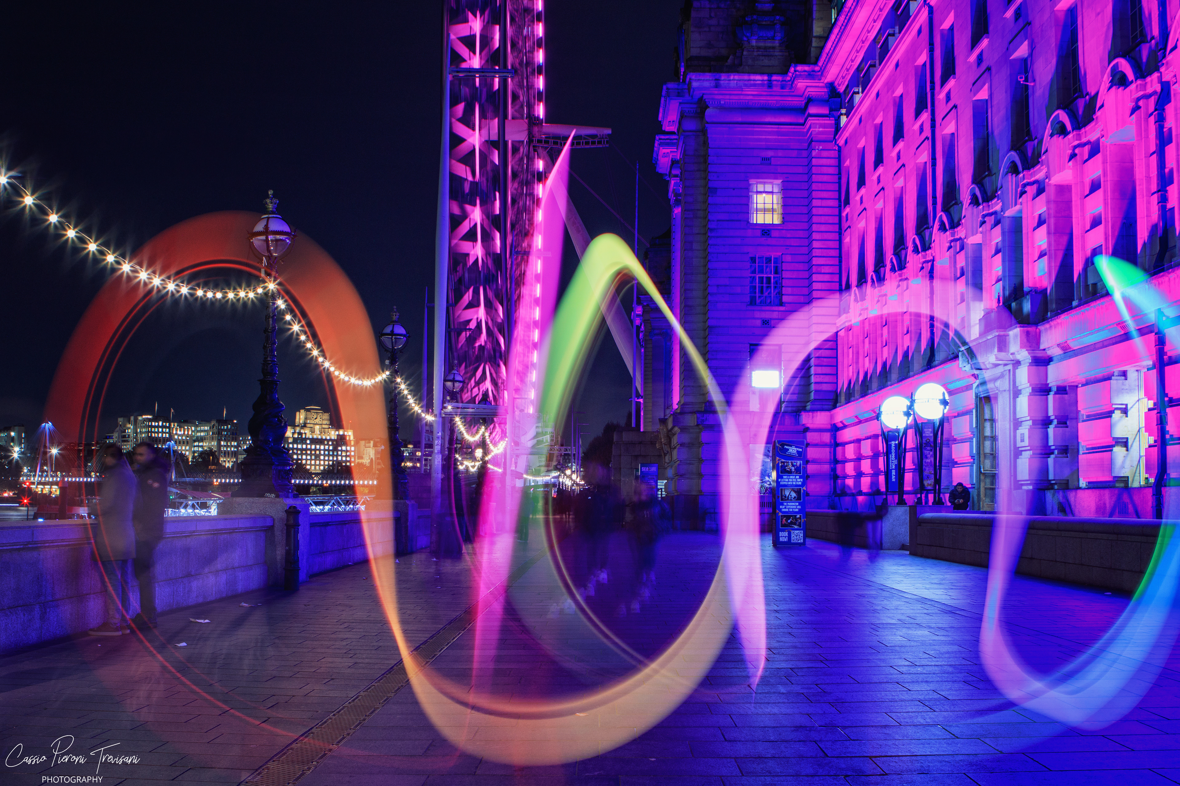 Neon light trails dance along the Thames, painting motion and color against London’s illuminated architecture.