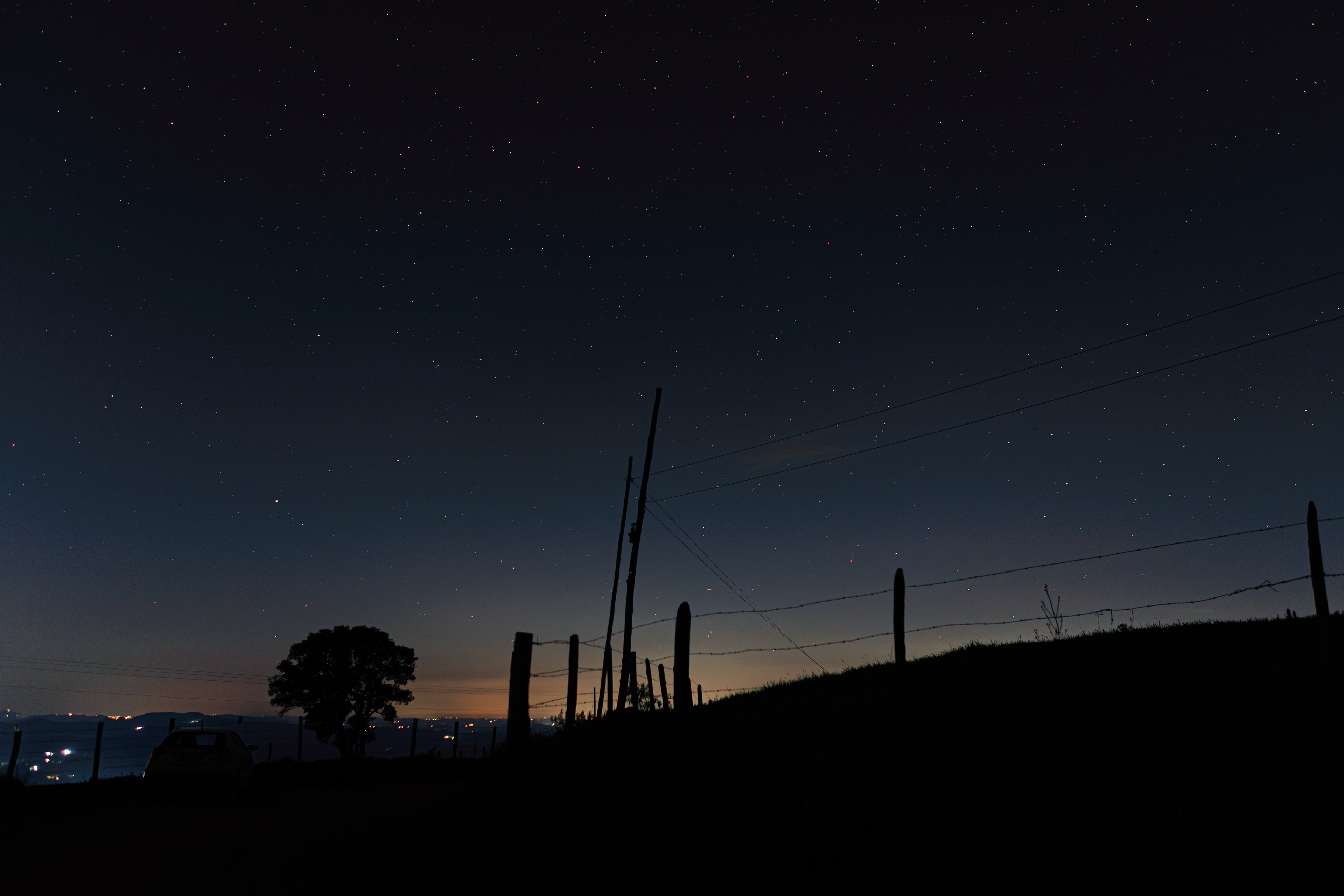 Supermoon rising behind clouds over Monte Alto Alegre, with rural landscape in the foreground.