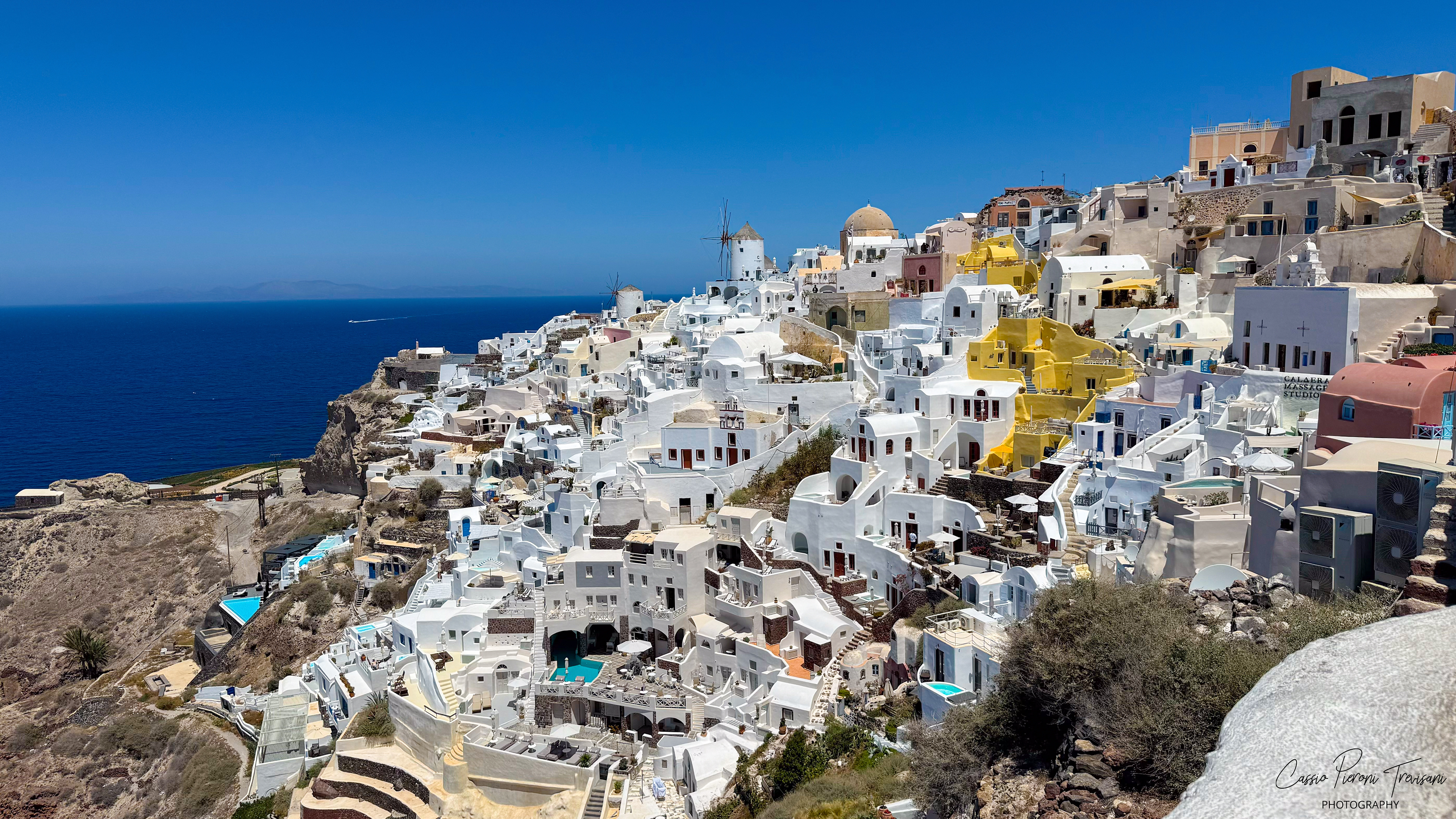 Whitewashed houses cascade down the cliffs of Oia, overlooking the vast Aegean Sea.