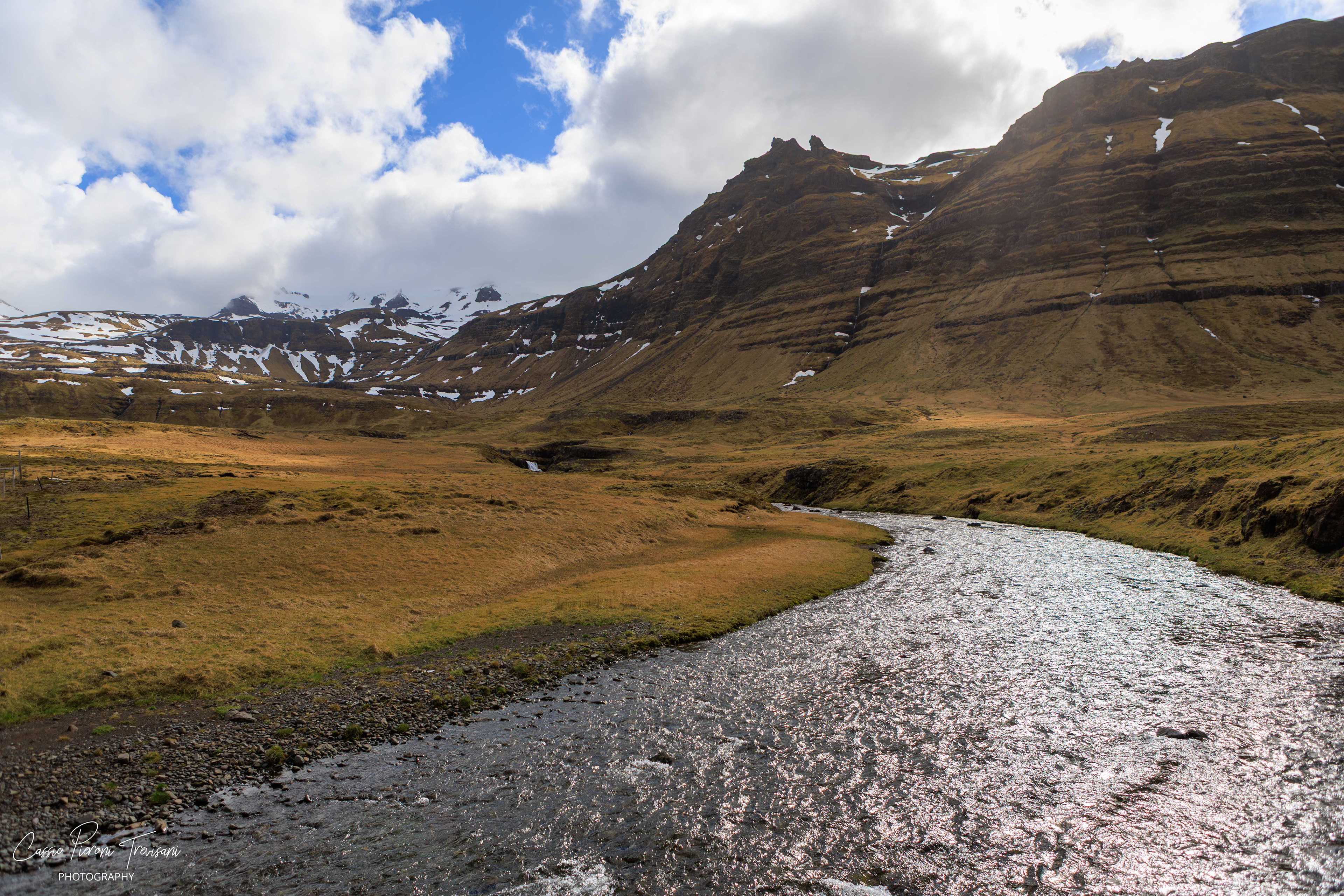 A glacial river winds through a broad mountain valley at Snæfellsjökull National Park, carrying light across the rugged textures of Iceland’s highlands.