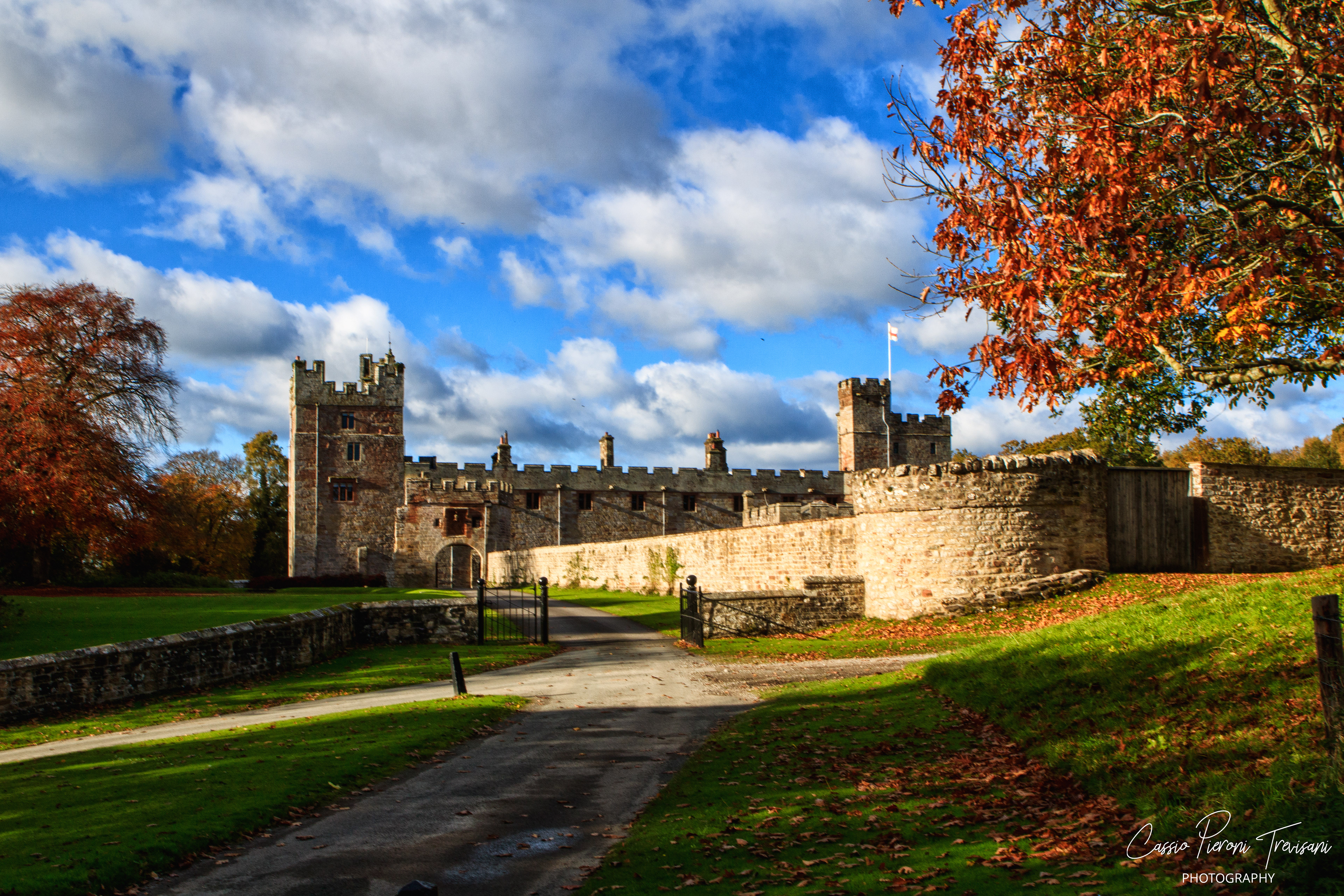 Aydon Castle bathed in warm autumn light, its medieval stone walls standing proudly against a vivid blue sky.