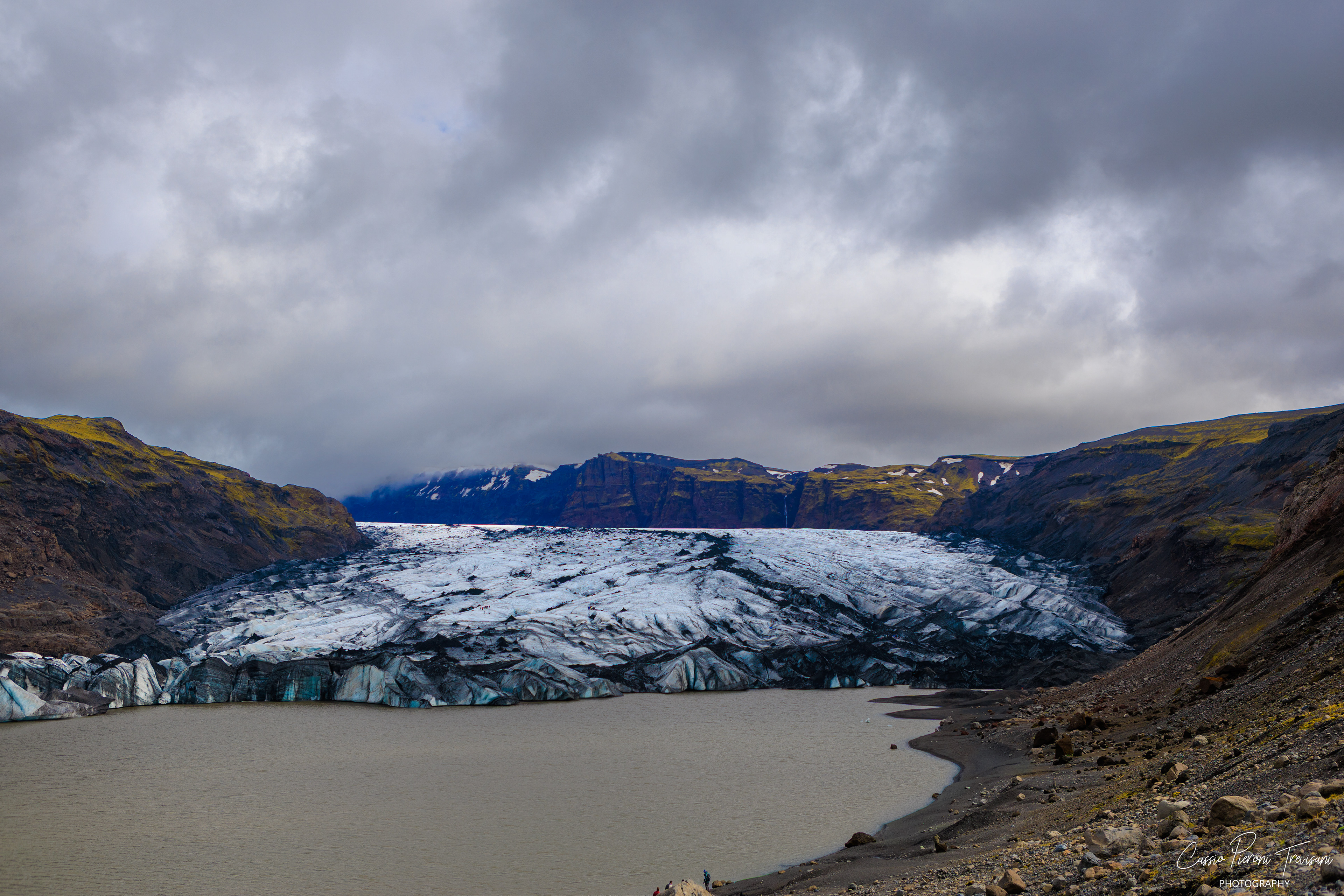 The glacier’s cracked surface reveals layers of white, blue, and black — ice shaped by time and volcanic terrain..