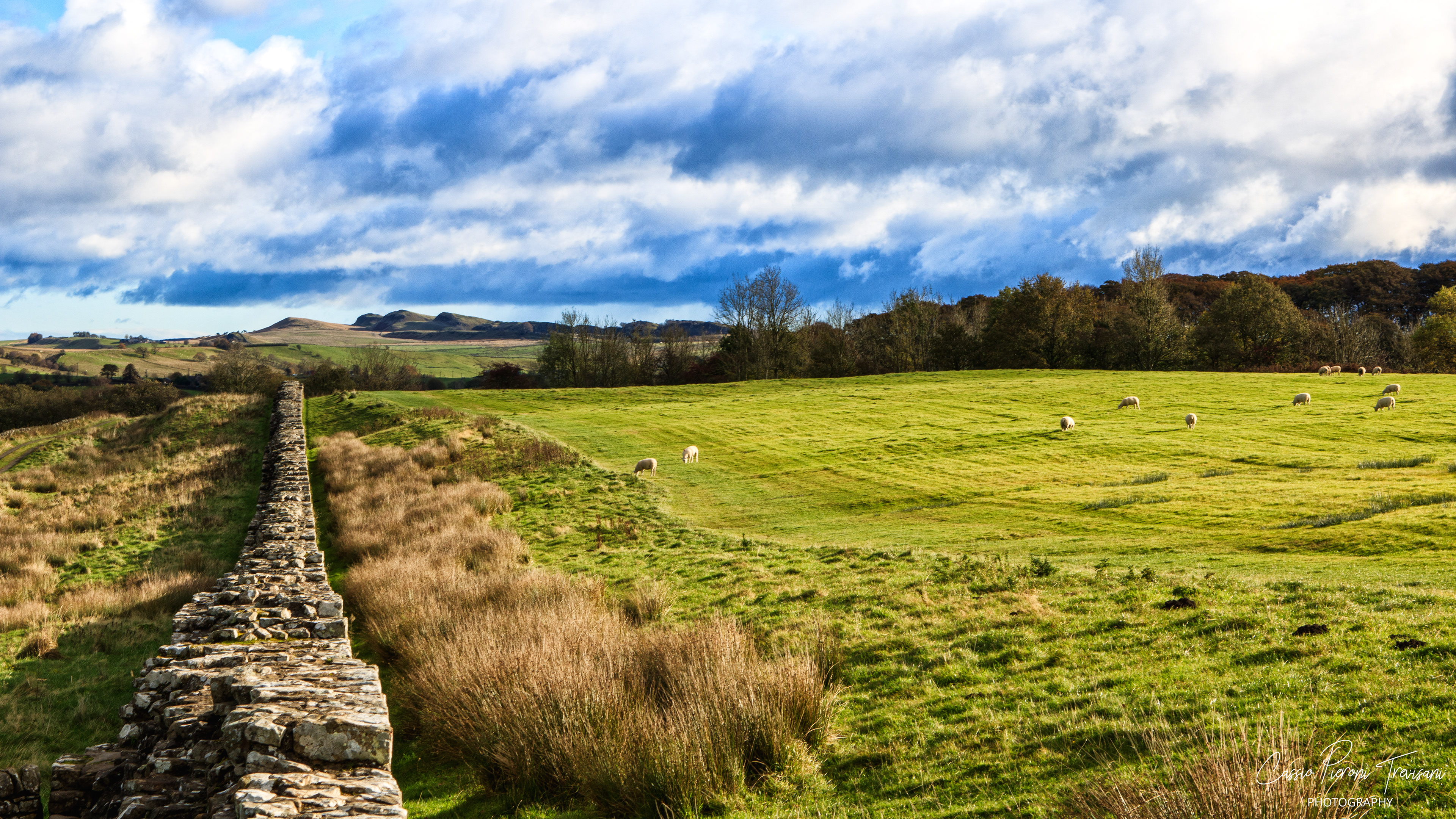Hadrian’s Wall cutting through rolling green fields beneath dramatic October skies, a timeless boundary shaped by history and nature.