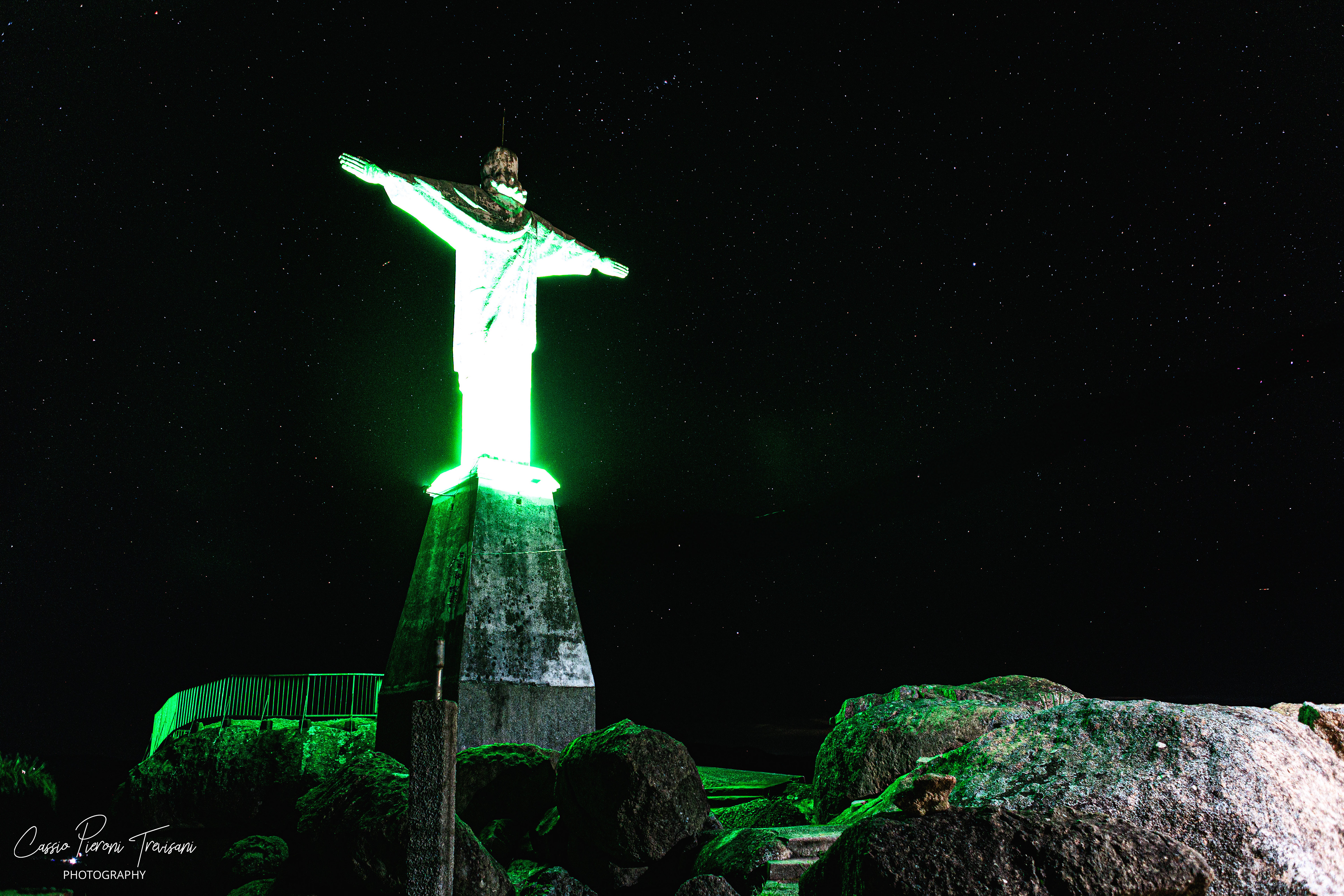 Night view of Mirante de Albertina with illuminated statue under starry sky.