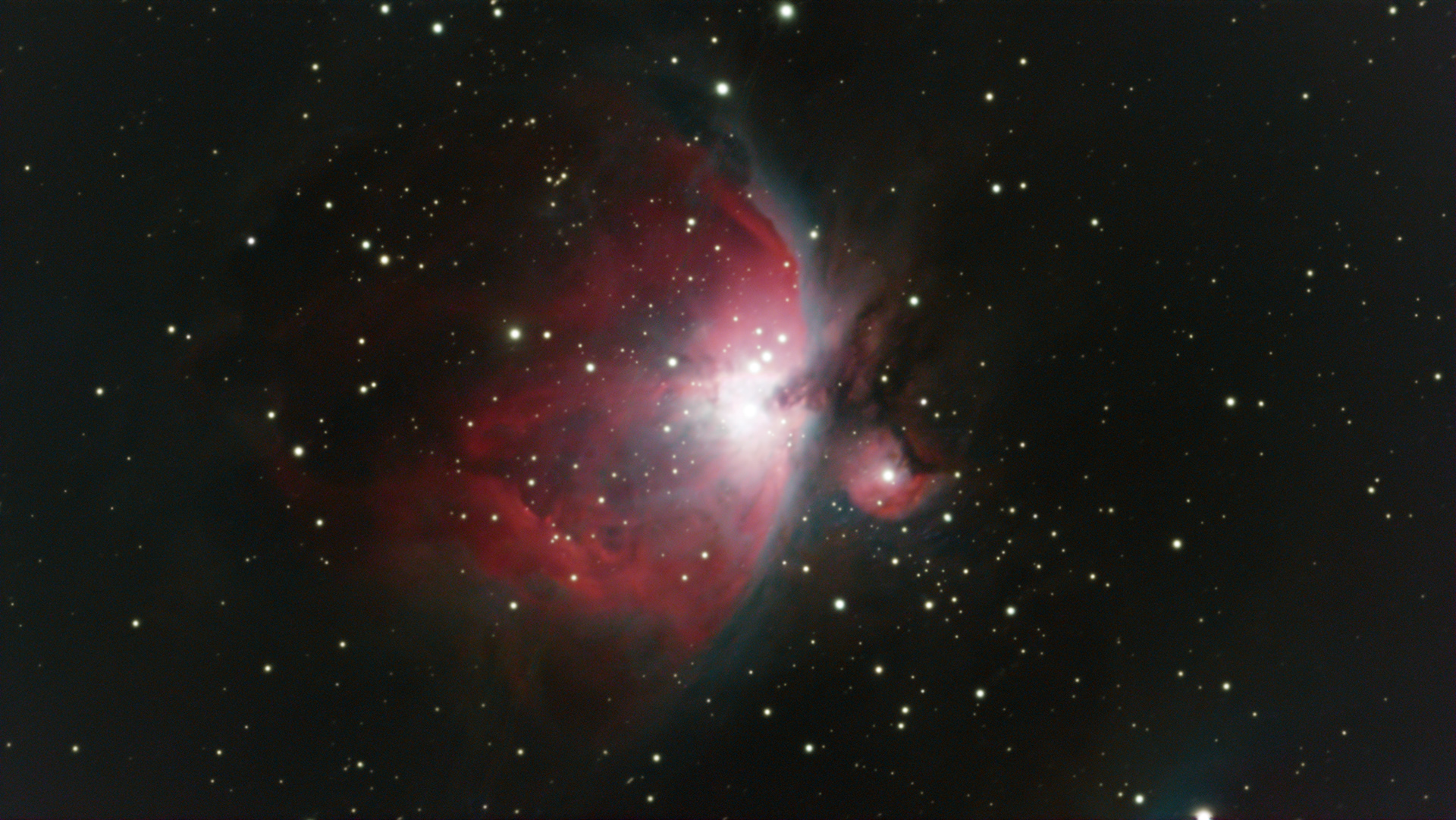 Astrophotography image of M42, the Orion Nebula, showing a bright white core surrounded by glowing red and pink nebula clouds against a dark star-filled sky.