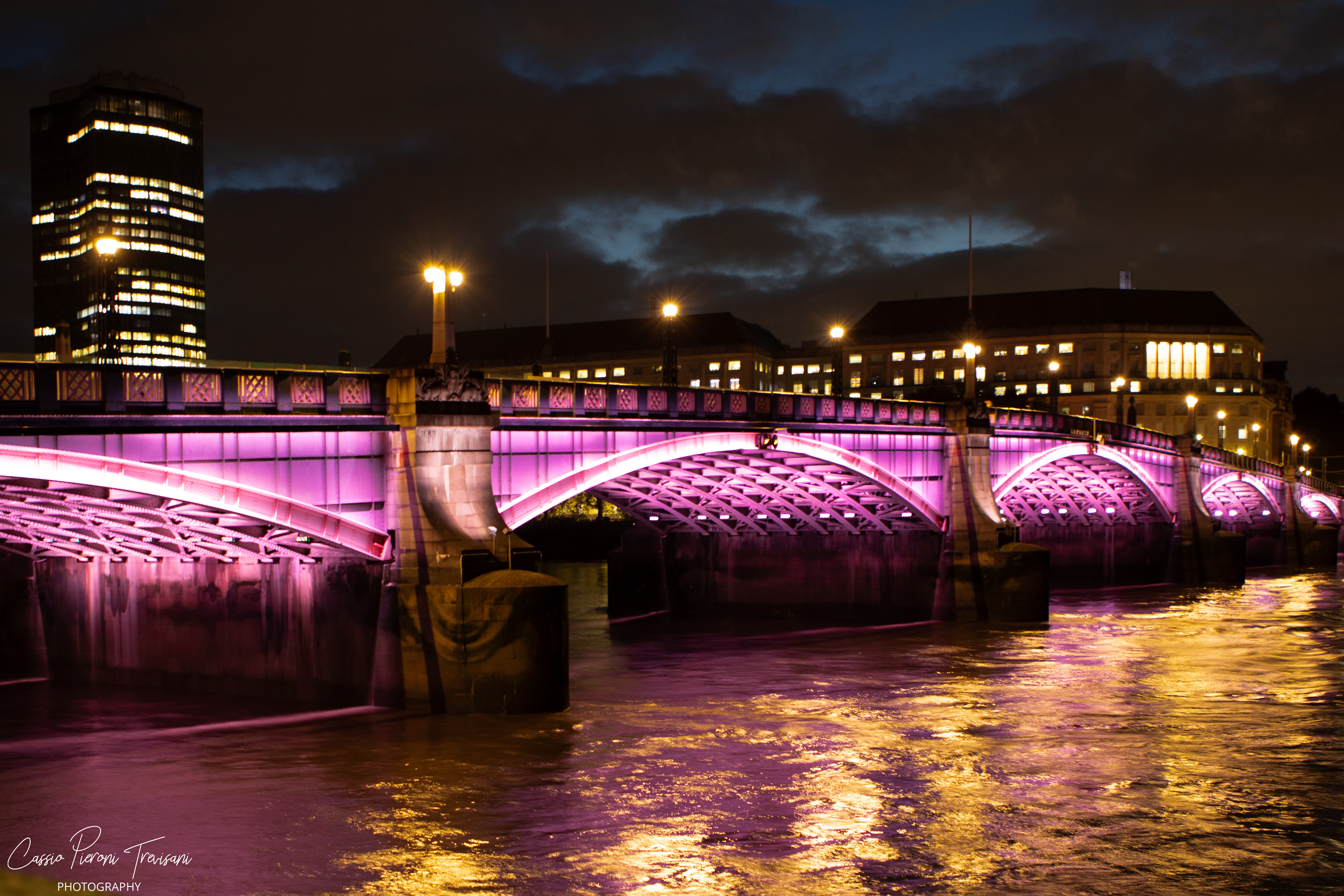 A wash of magenta light transforms Lambeth Bridge into a luminous ribbon across the Thames, where architecture, reflection, and night converge.