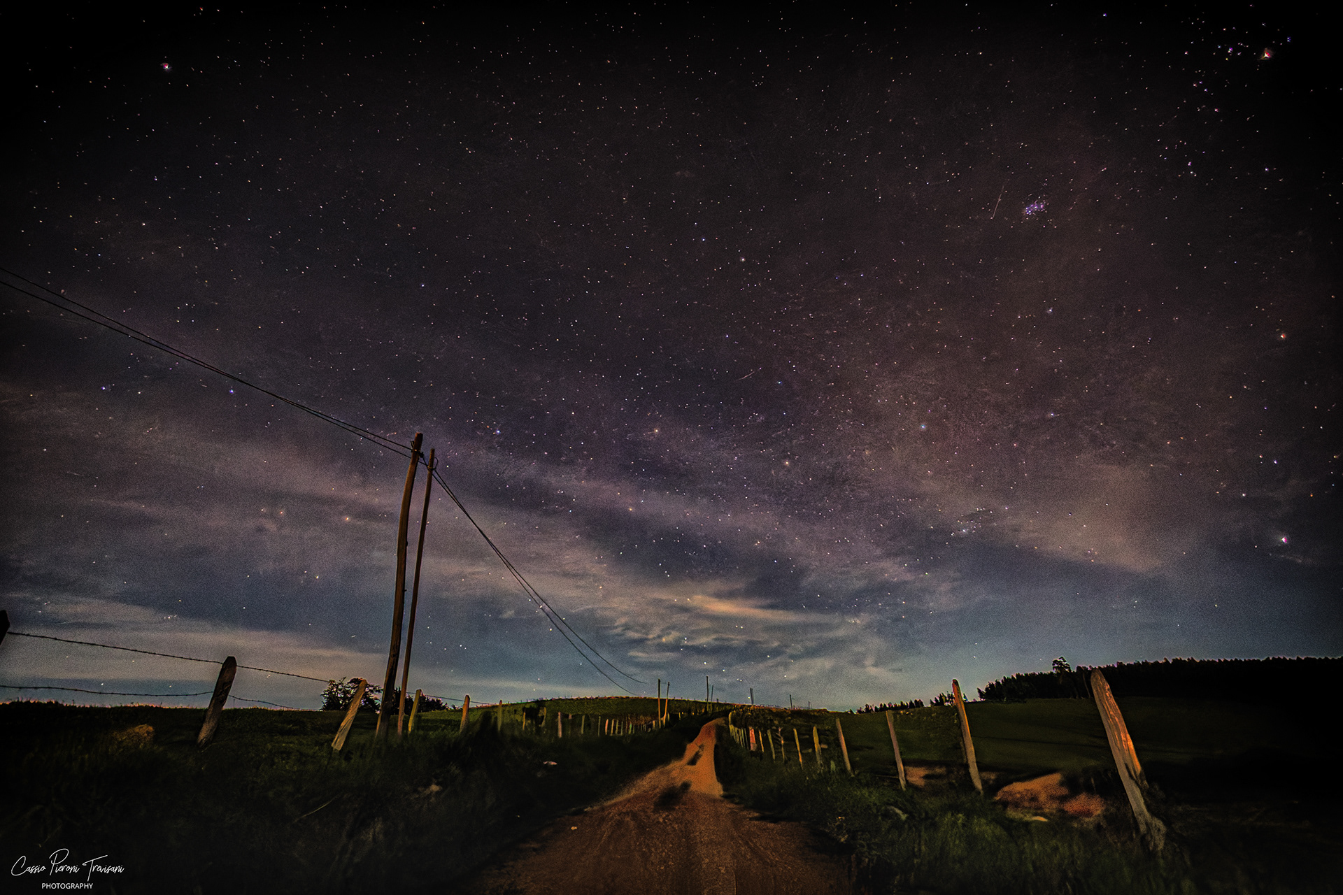 Dirt road at night leading through a rural landscape beneath the Milky Way, with stars filling the sky in Jacutinga, Minas Gerais, Brazil.