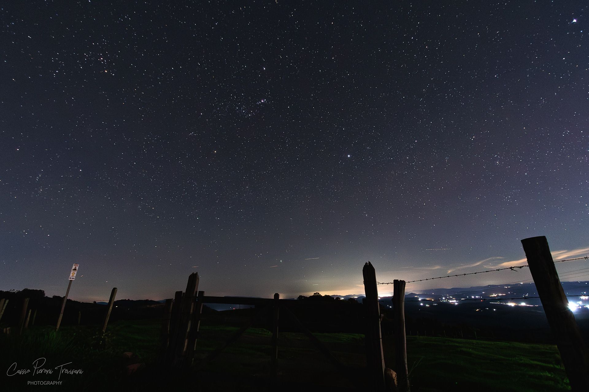 Star-filled night sky over Jacutinga countryside with wooden fence in foreground.