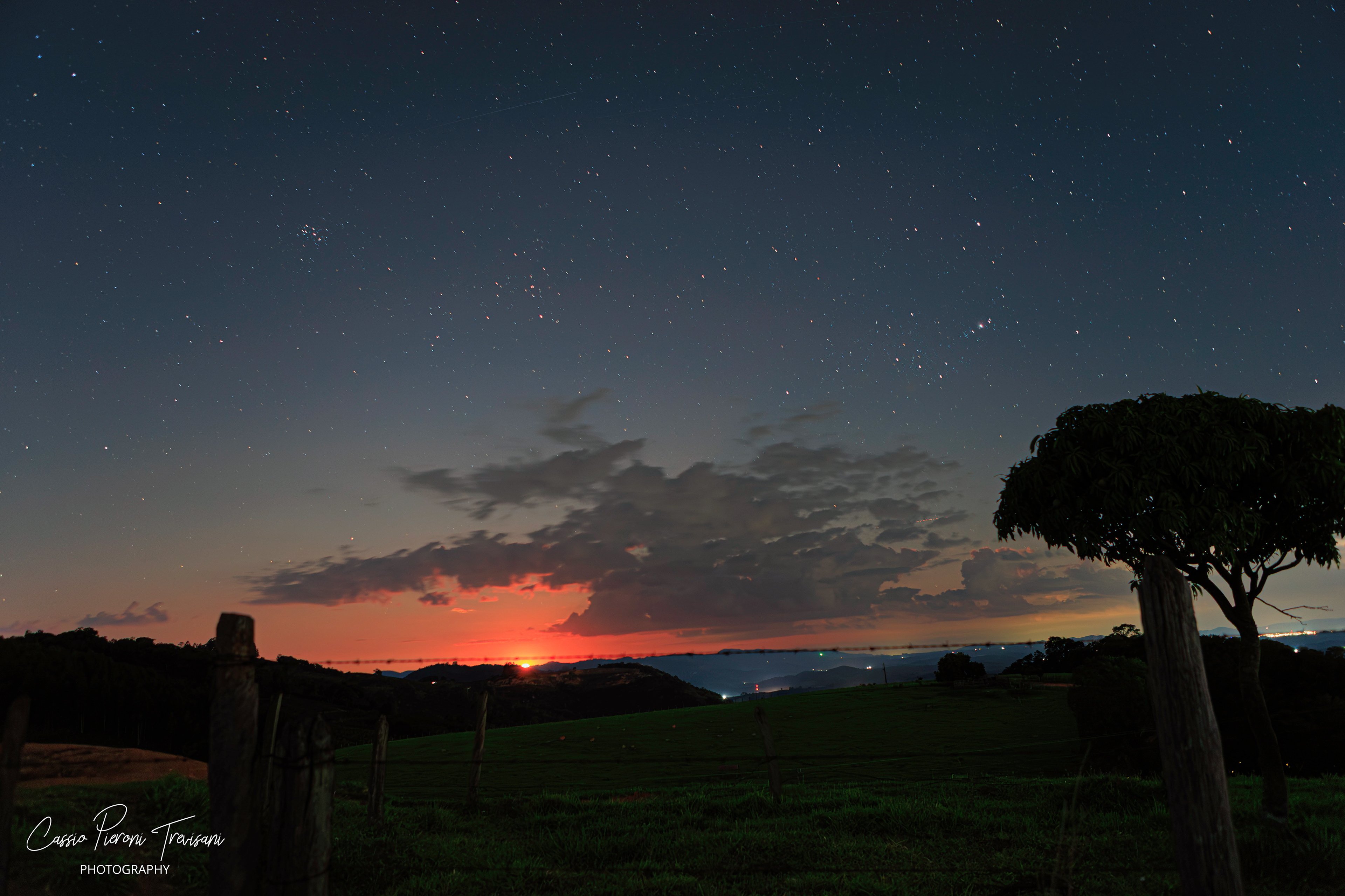 Supermoon rising behind clouds over Monte Alto Alegre, with rural landscape in the foreground.