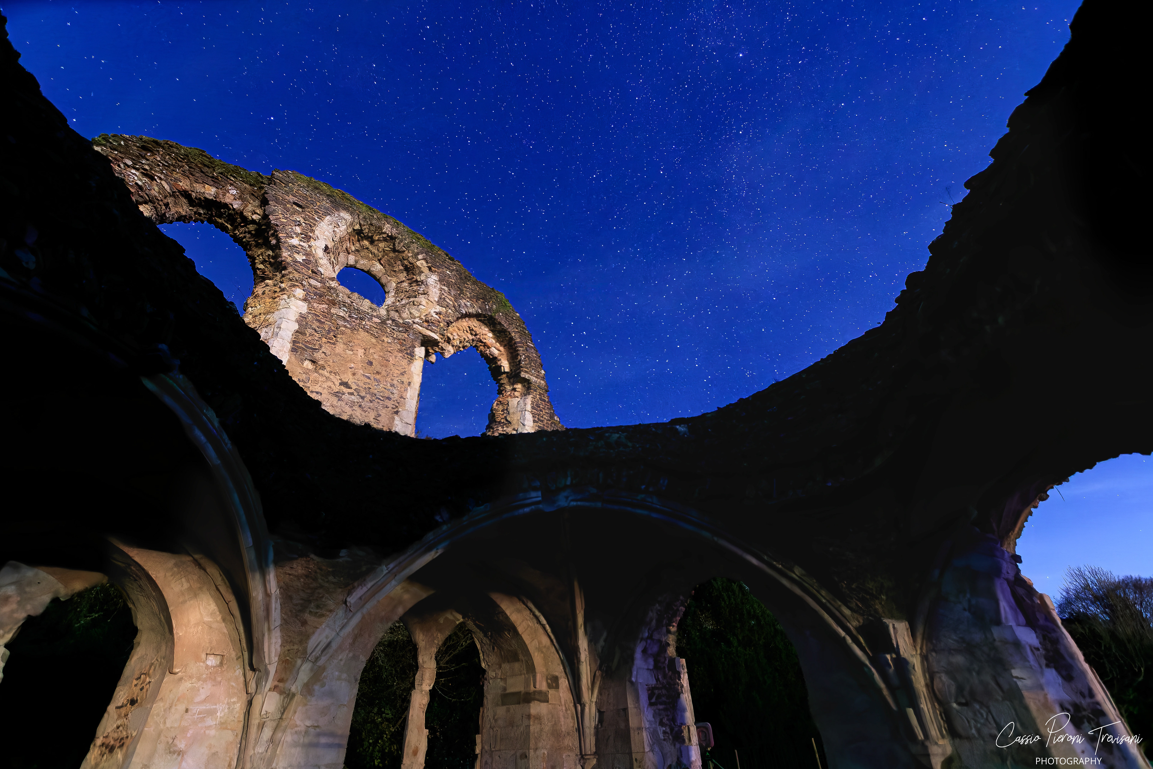 Interior view of Waverley Abbey arches looking upward toward a starry night sky.