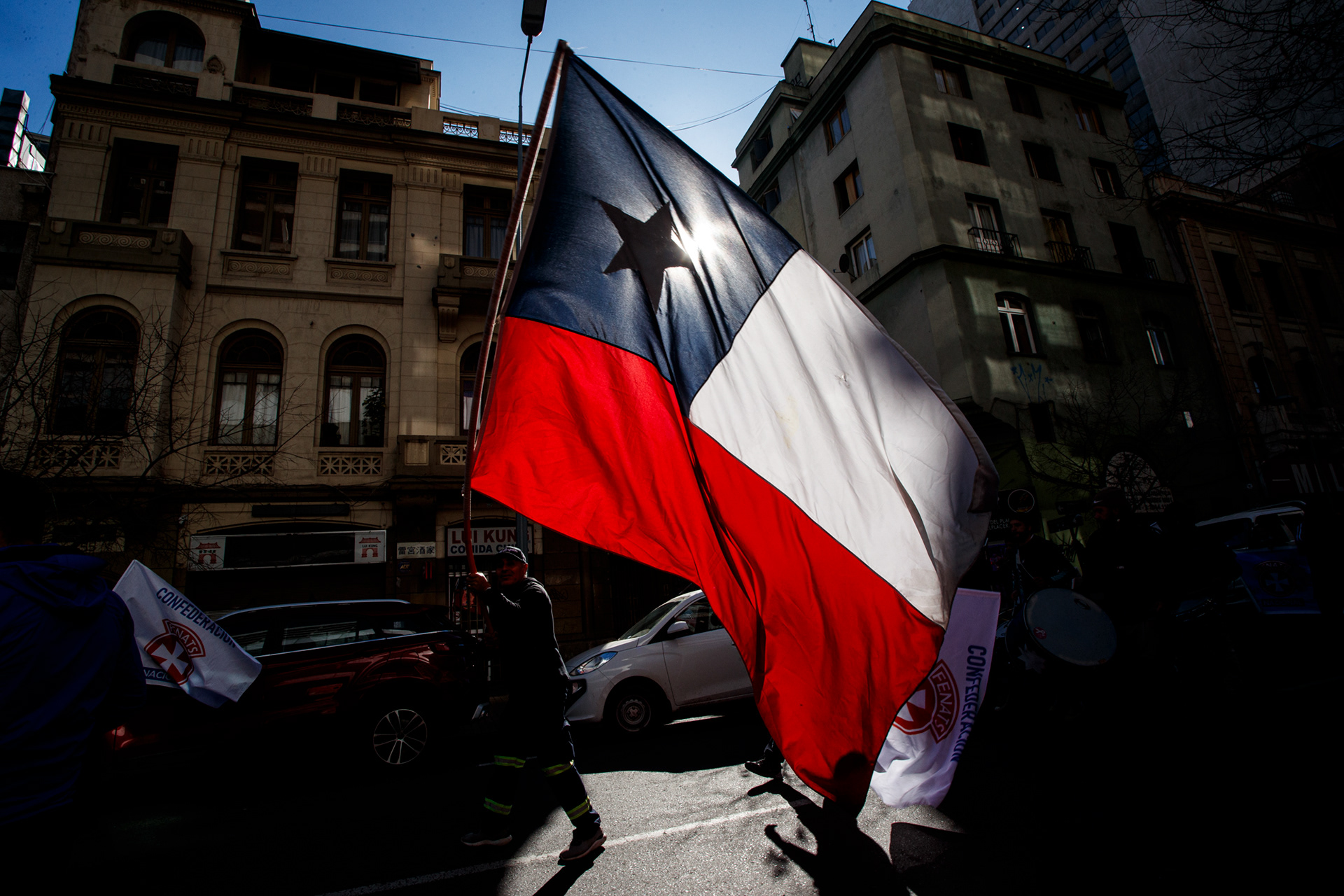 19 de junio 2024 / SANTIAGO Un manifestante sostiene una bandera chilena durante una marcha de la CONFUSAM en la capital.