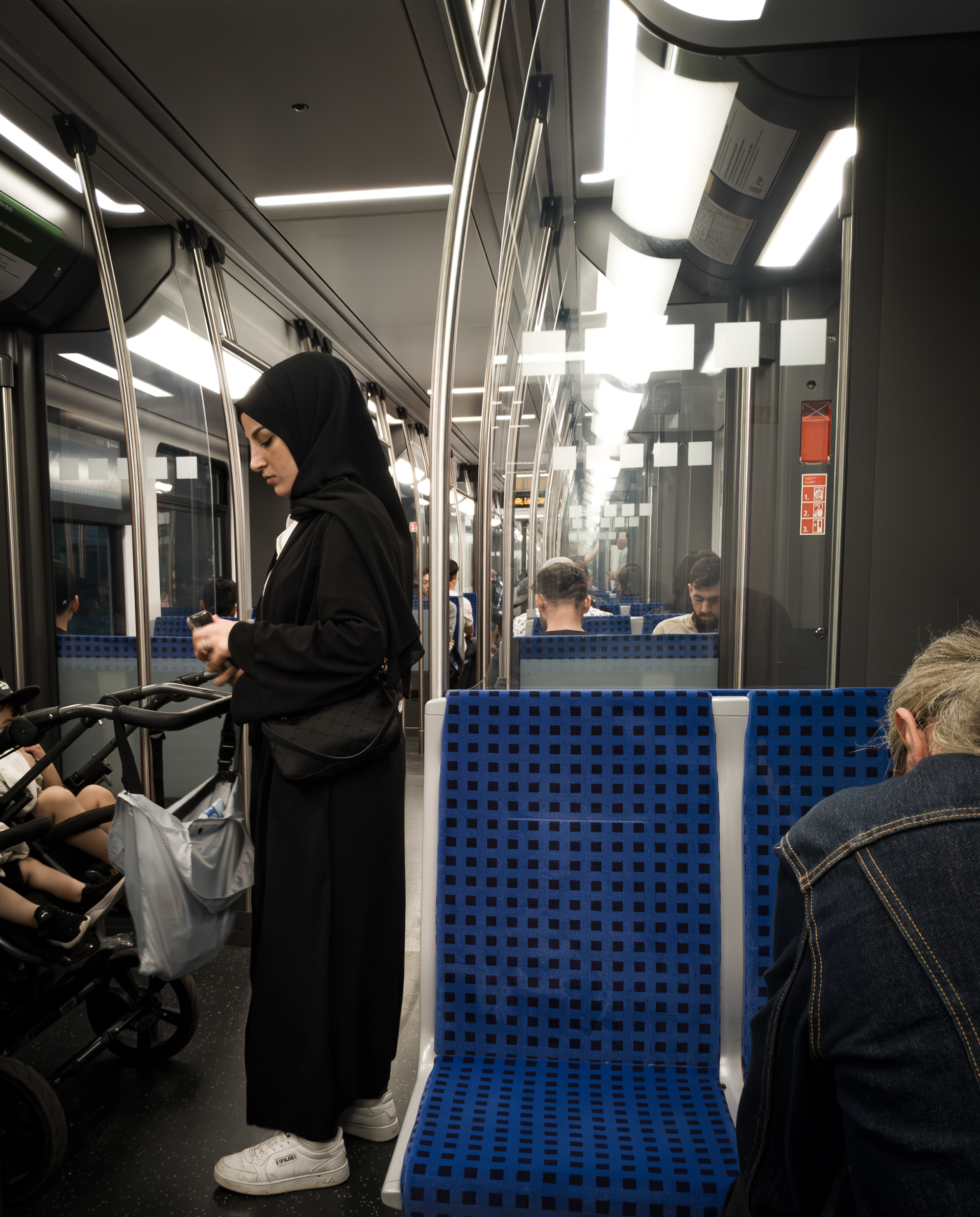 "Uma mãe agredida". Essa mulher foi agredida verbalmente pelo homem sentado à direita porque as crianças no carrinho choravam. S-Bahn, Berlim, junho de 2023