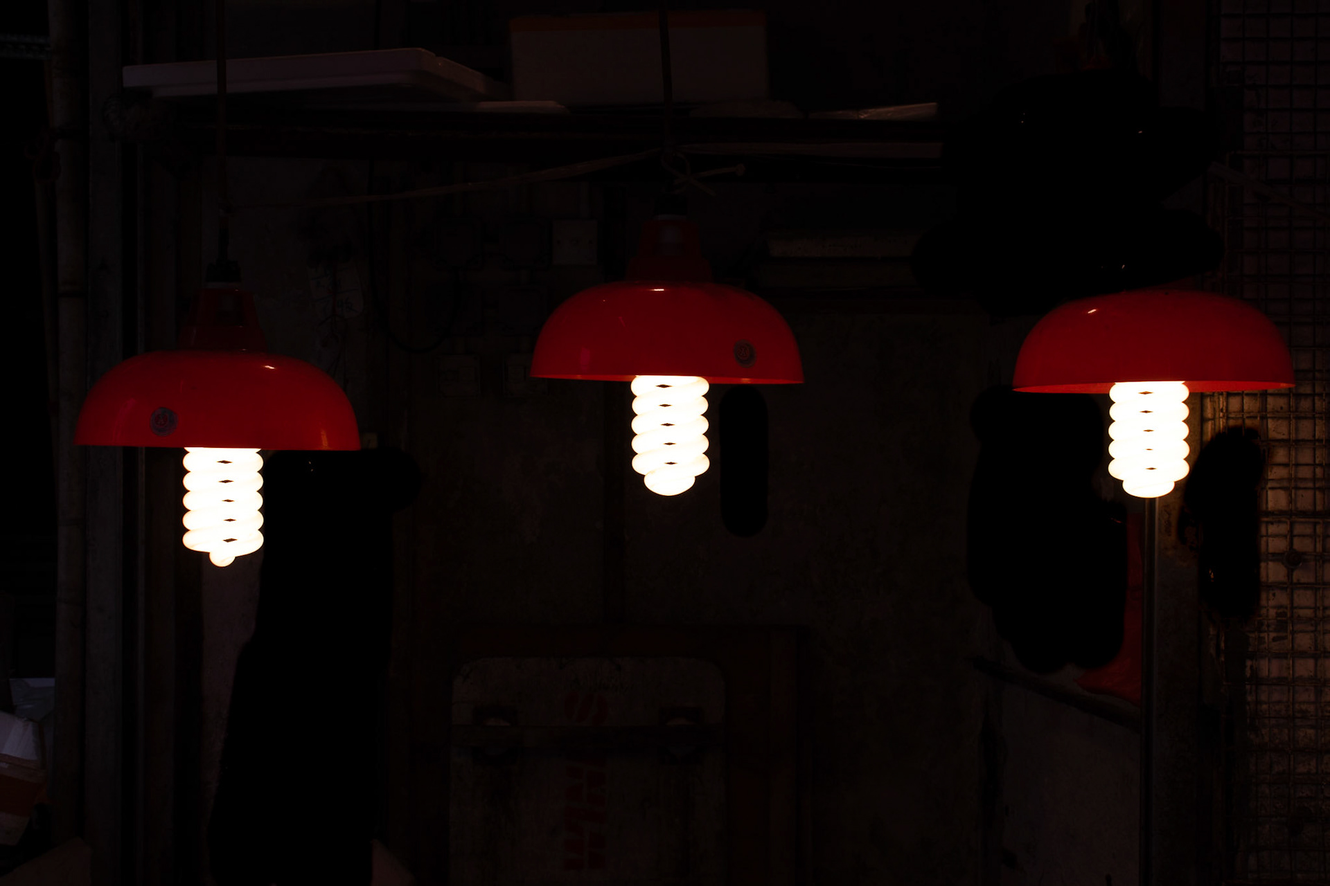 Three energy saving lamps with red shades against a black background