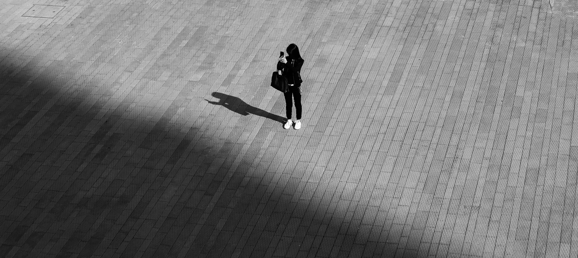 A woman looks at her phone alone in a square in Central, Hong Kong
