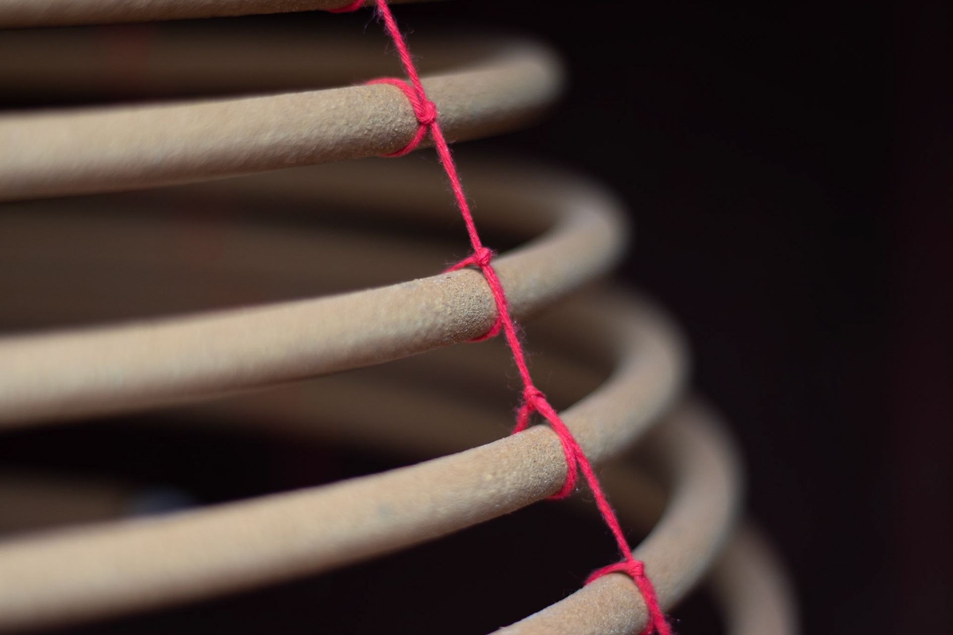 A spiral incense burner hangs against a black background.