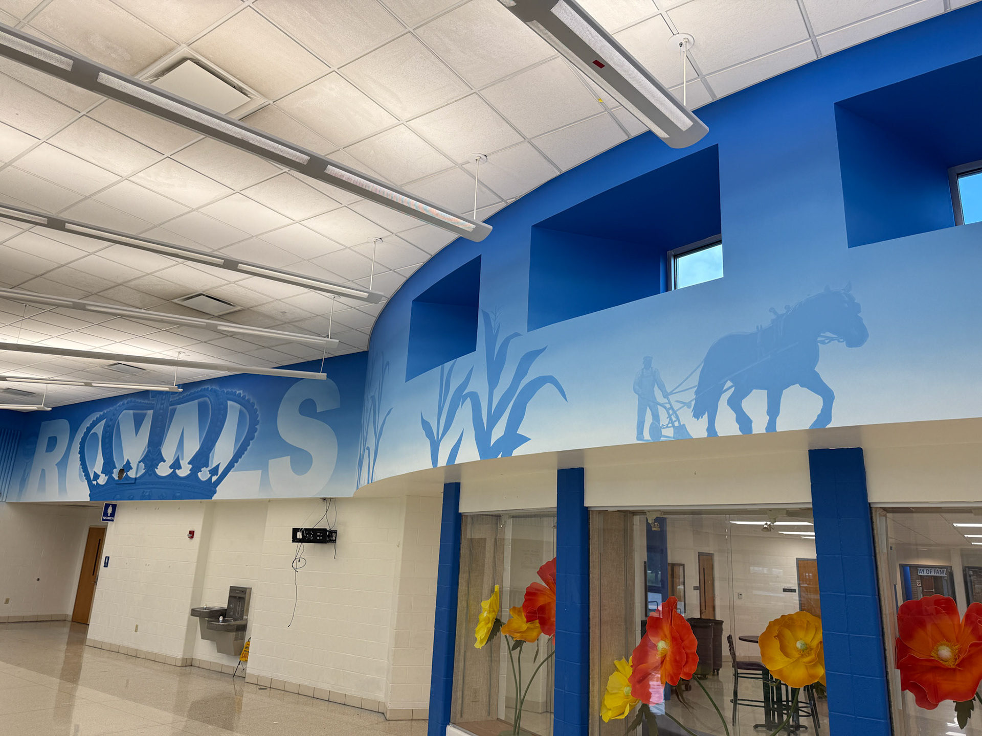 "ROYALS" logo + partial next section with corn stalks and man with horse plow silhouette