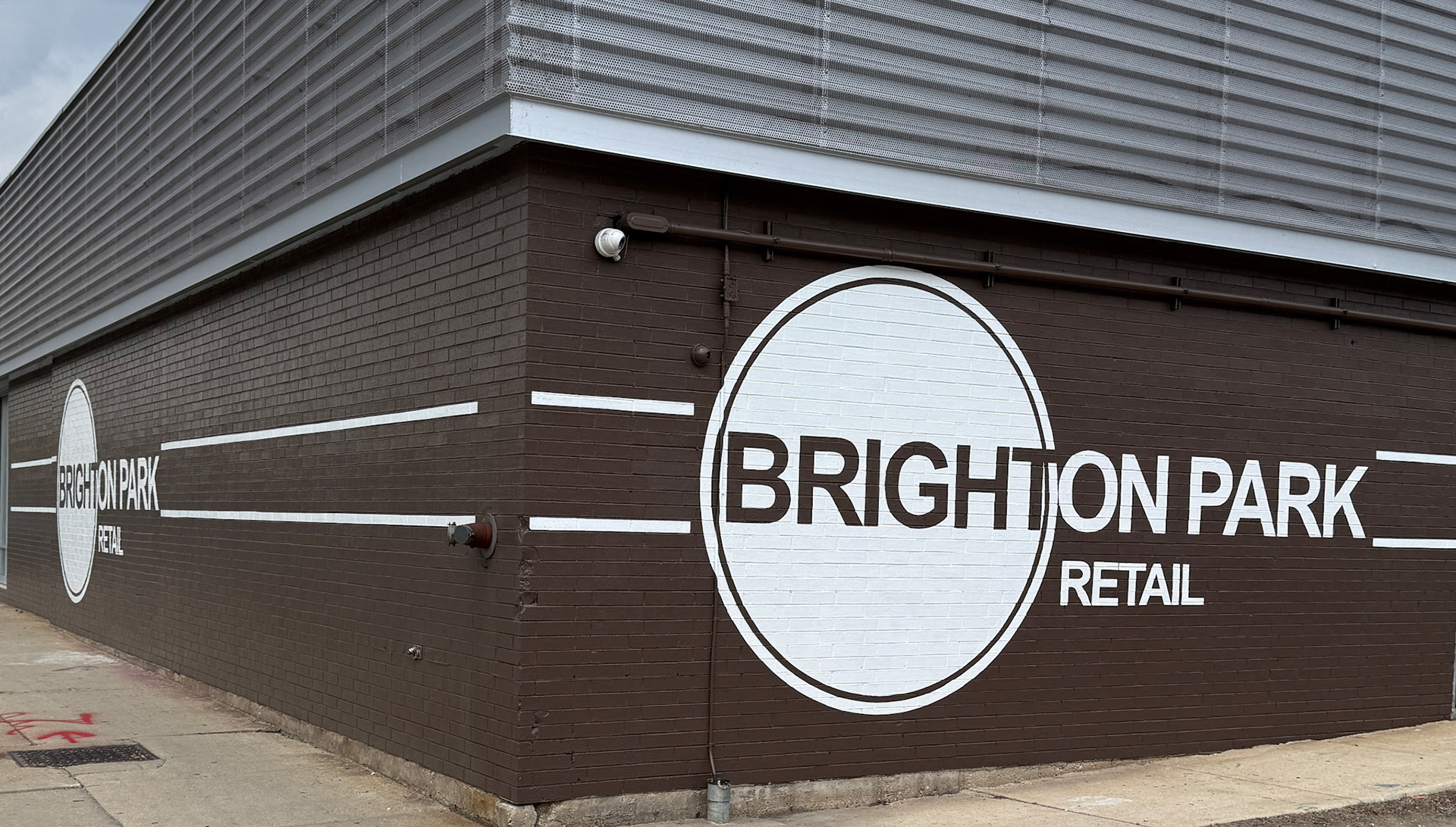wide view showing the full corner of the building with logos on both sides, brick walls