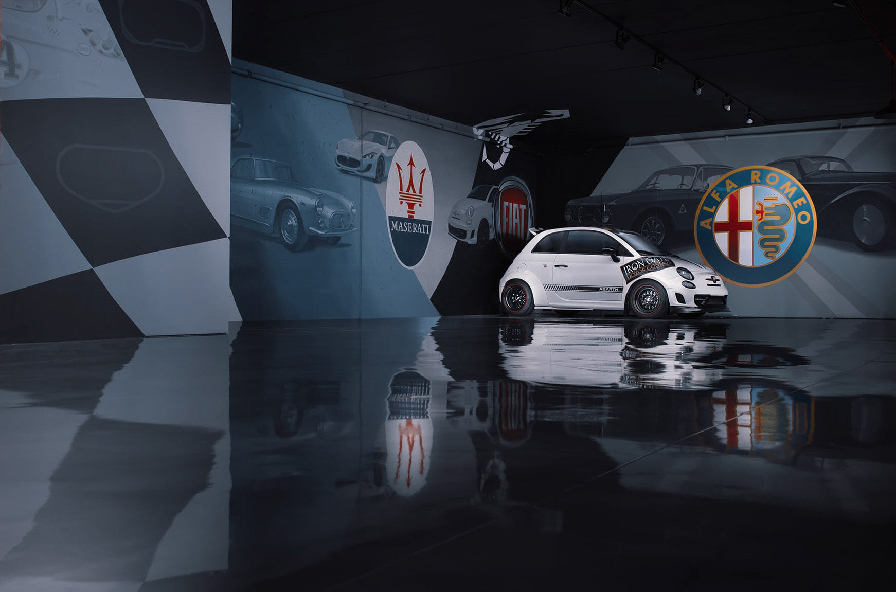 Hand-painted Alfa Romeo and Fiat themed mural in the luxurious basement of Iron Gate Motor Condos, Naperville, Illinois – custom automotive signage featuring classic Alfa Romeo models, Fiat logos, Maserati accents, and checkered racing floor, with white Alfa Romeo car displayed in front. Photo by JR Photon