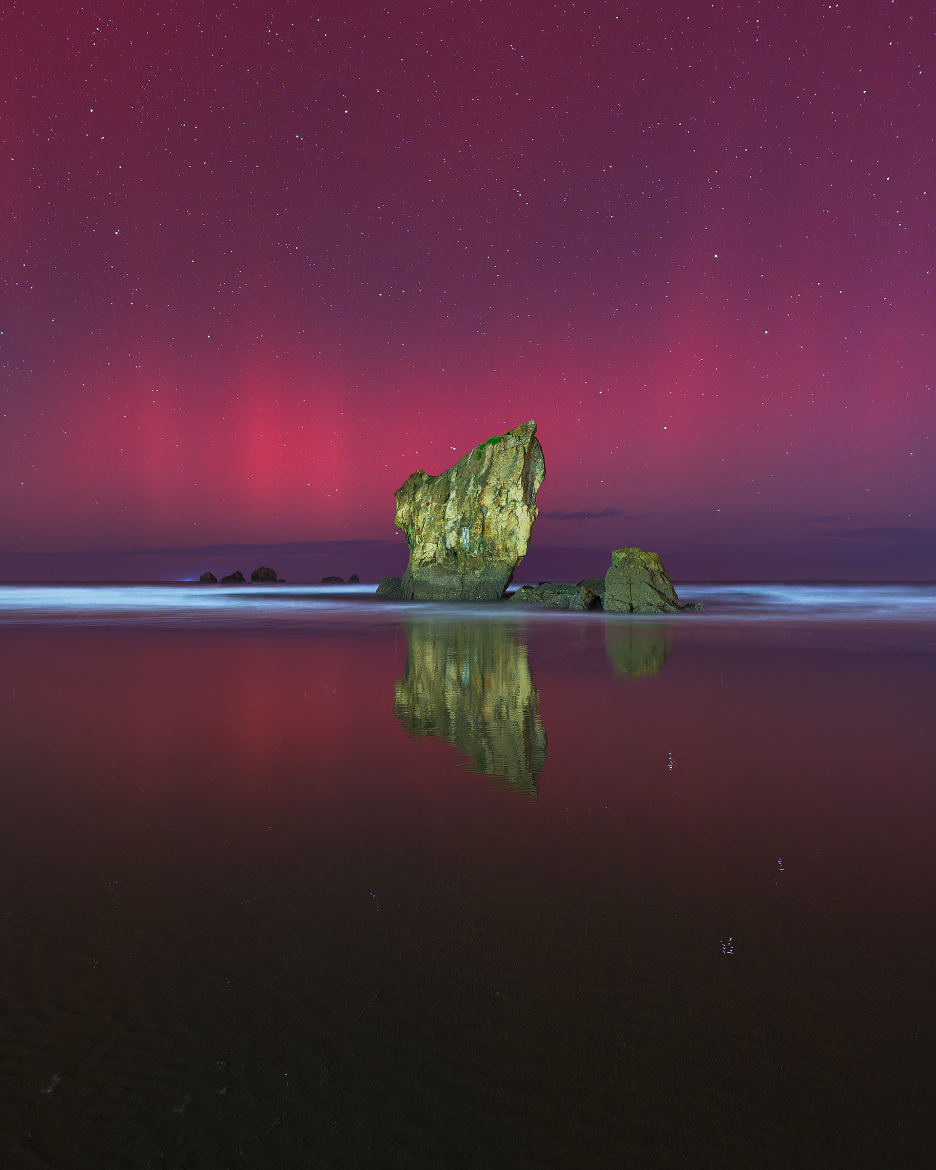 Espectacular aurora boreal sobre la Playa de Aguilar, Asturias en octubre de 2024, con luces en tonos rojos, rosa y morados 
