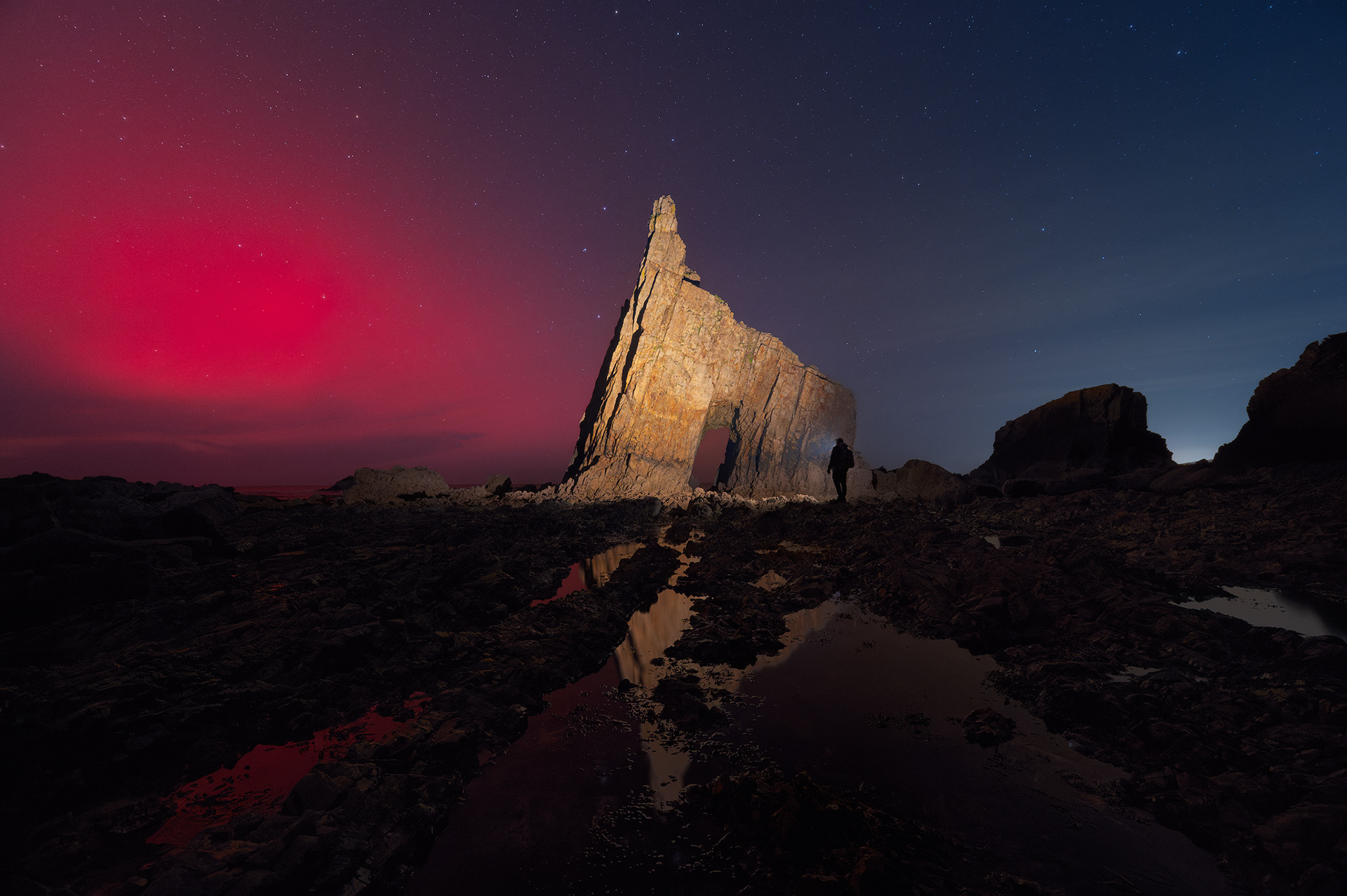 Fotografía de la aurora boreal roja sobre los acantilados de la Playa de Campiecho, Asturias