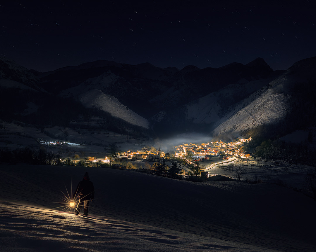 caminando con una linterna hacia el pueblo de soto de agues en el parque natural de redes, con una buena nevada en la noche
