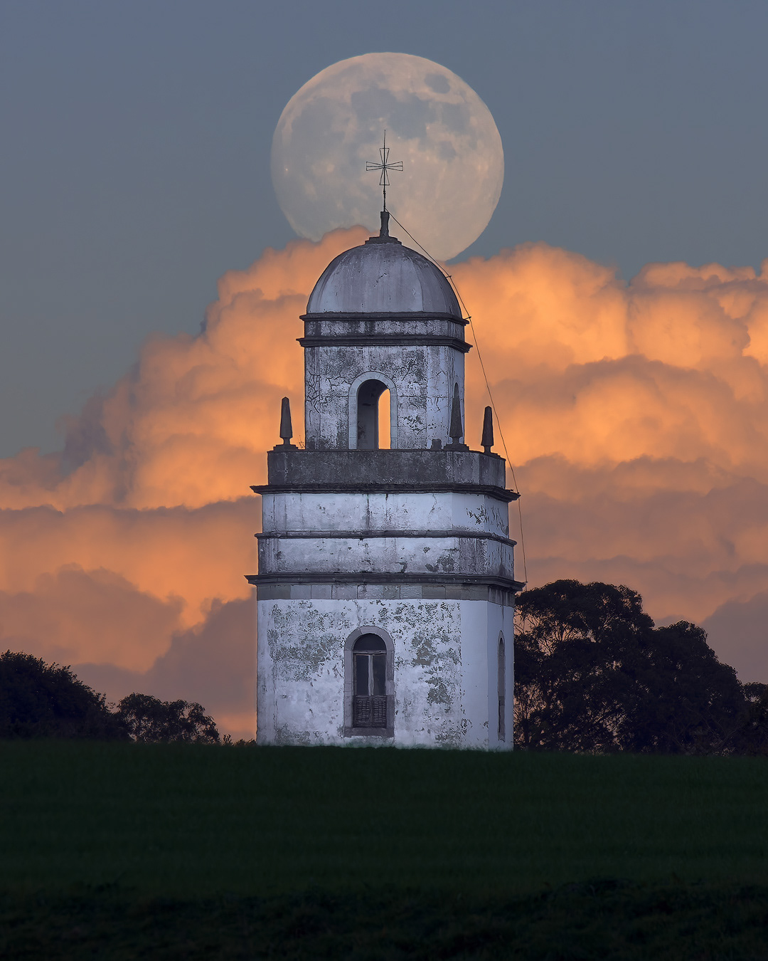 Lunisticio de 2024 en san martin de luiña, detras de la iglesia asoma entre nubes la gran luna 