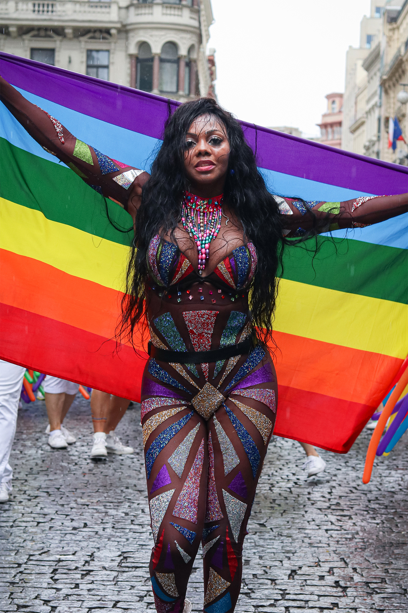 Reportážní fotografie jedné z účastnic průvodu Prague Pride nesoucí duhovou vlajku
