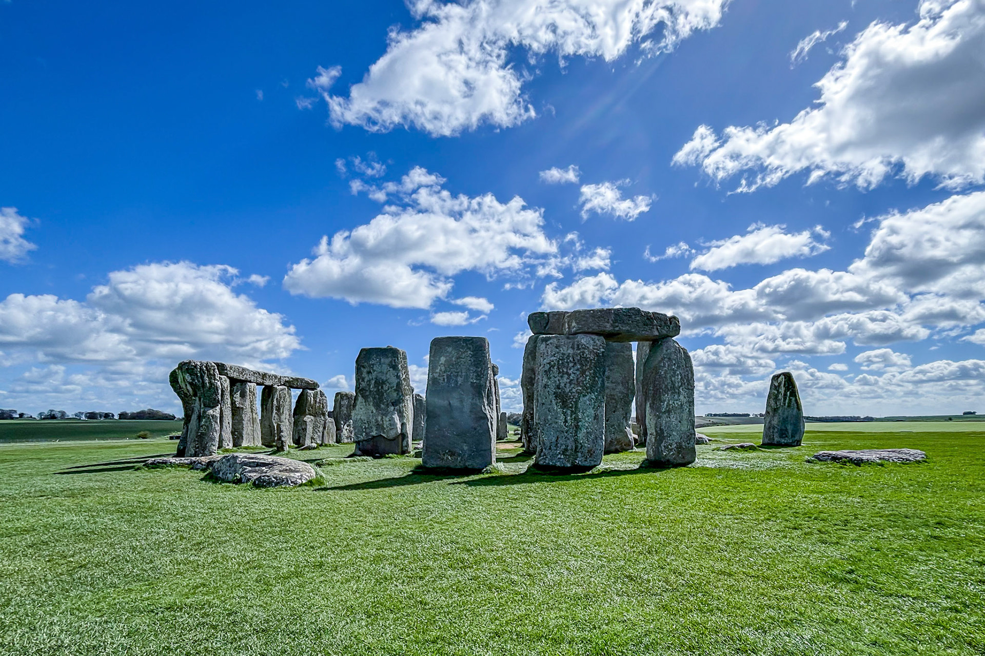 Stonehenge, green grass, and blue sky.