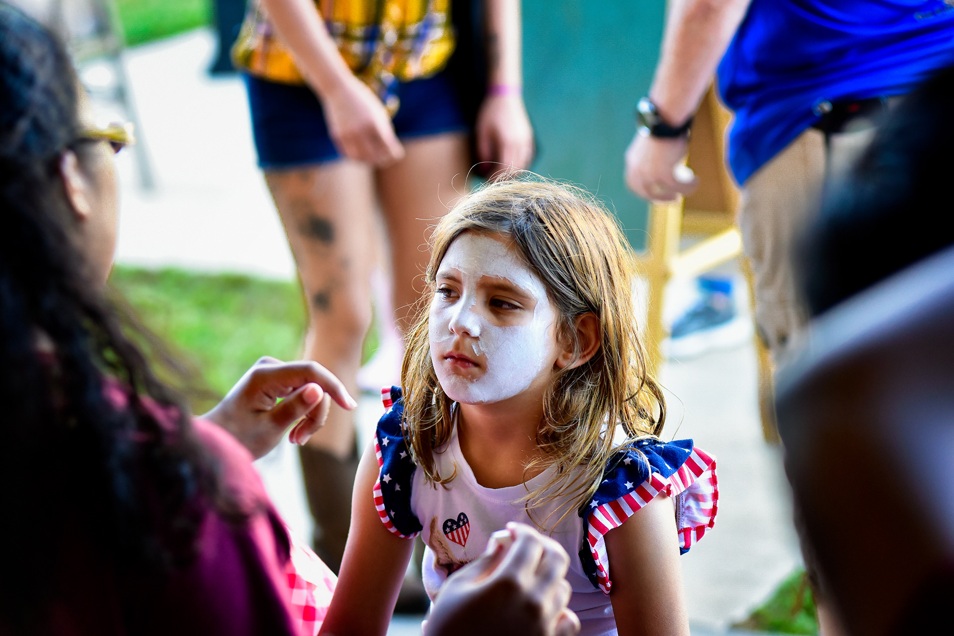 A young girl has her face painted.