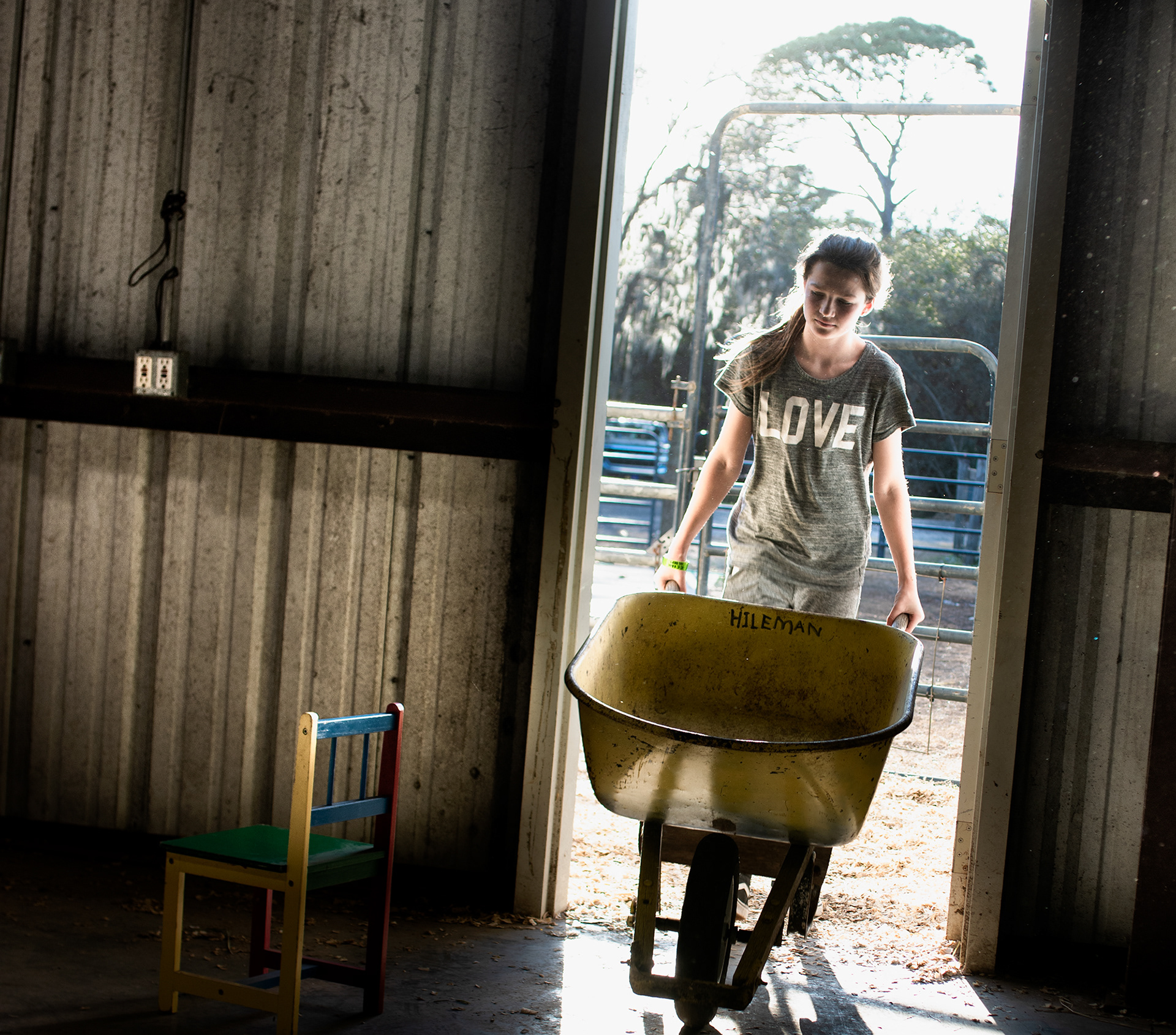 A young girl brings fresh bedding to her goat, before auction.