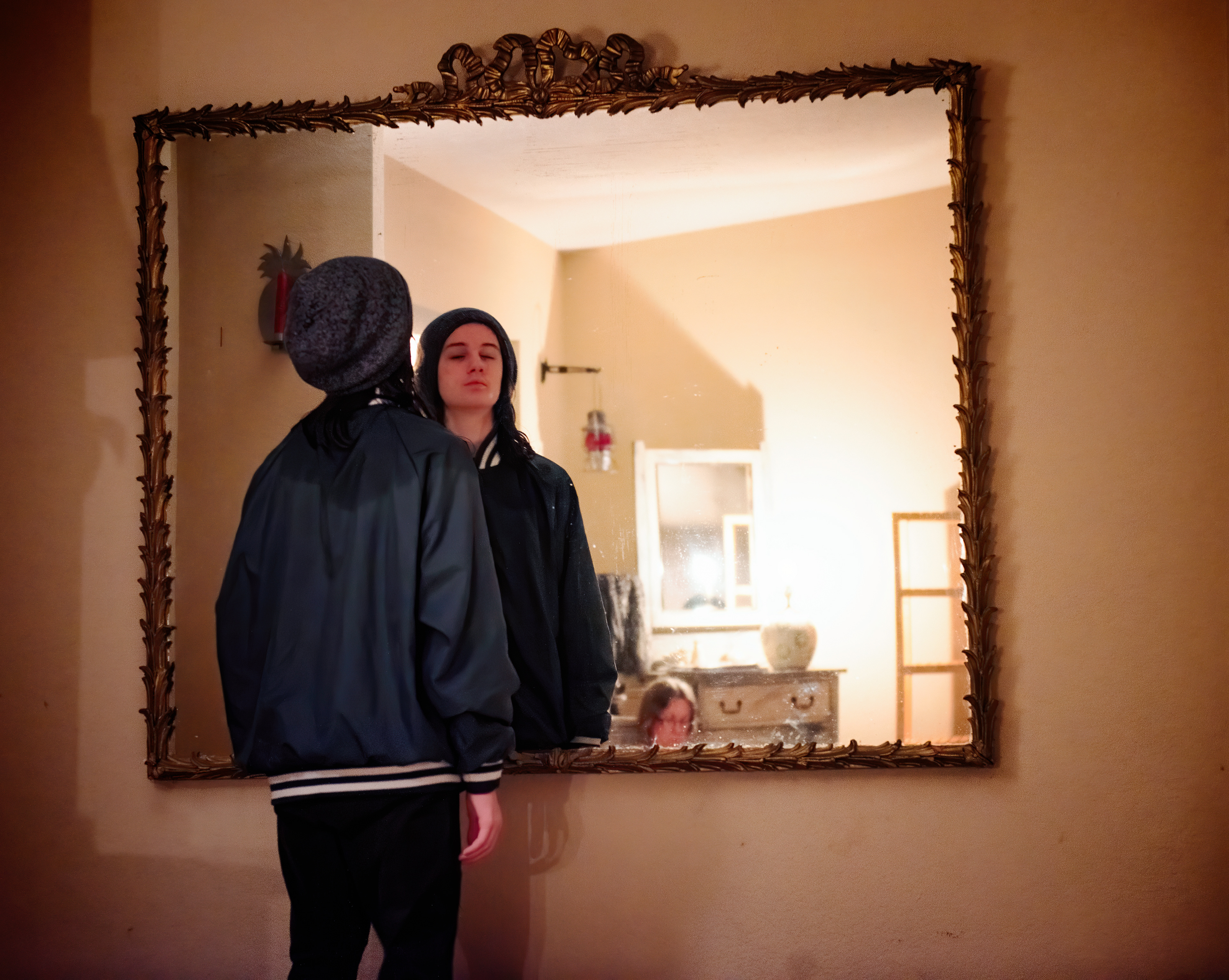 My son looks into a mirror at our front door entrance. 