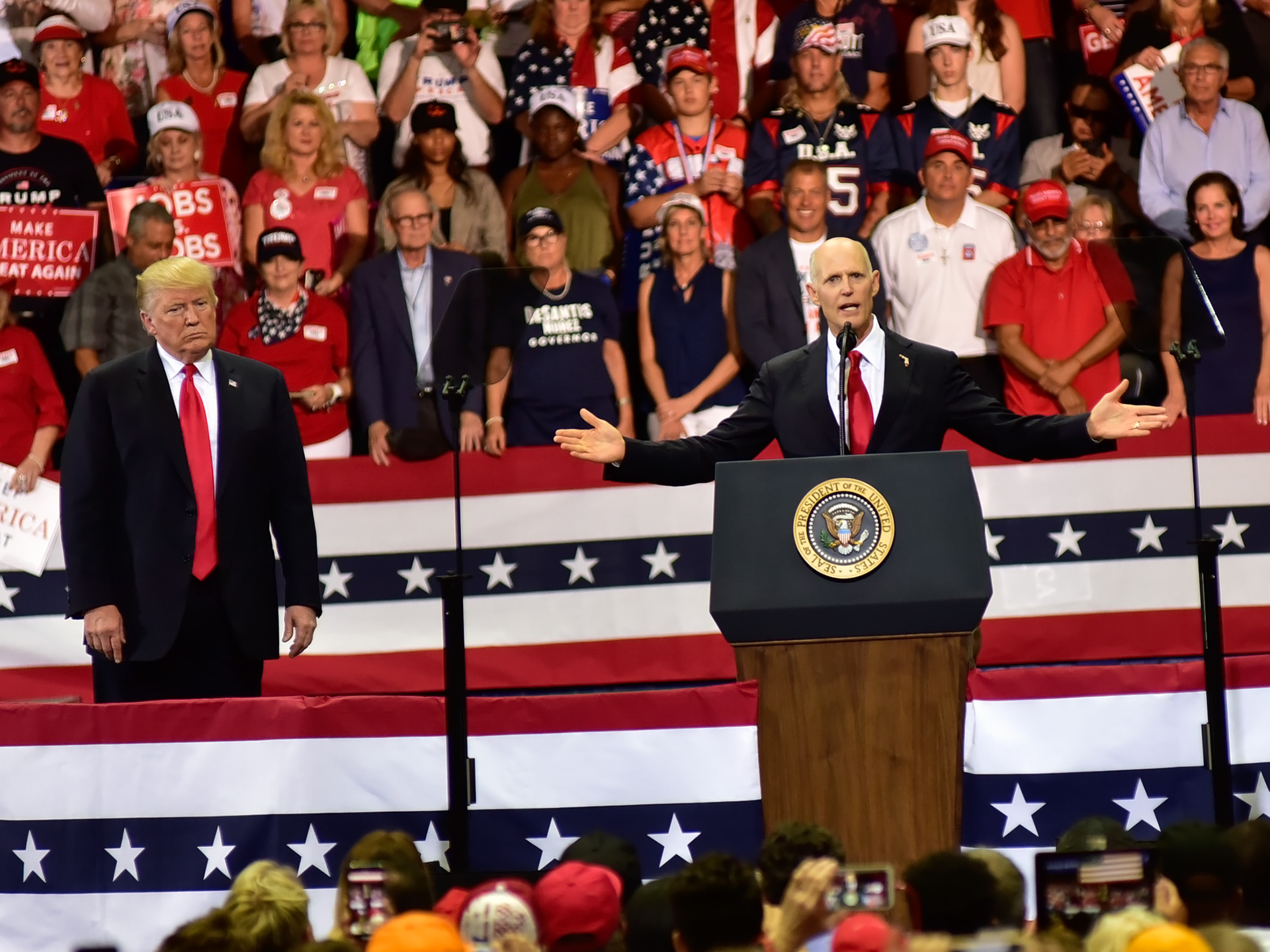 Florida Governor Rick Scott gestures to a capacity crowd, as President Donald Trump observes, during a rally in Estero Florida, on Wednesday, Oct 31, 2018.  Scott is running for U.S. Senate against Bill Nelson.