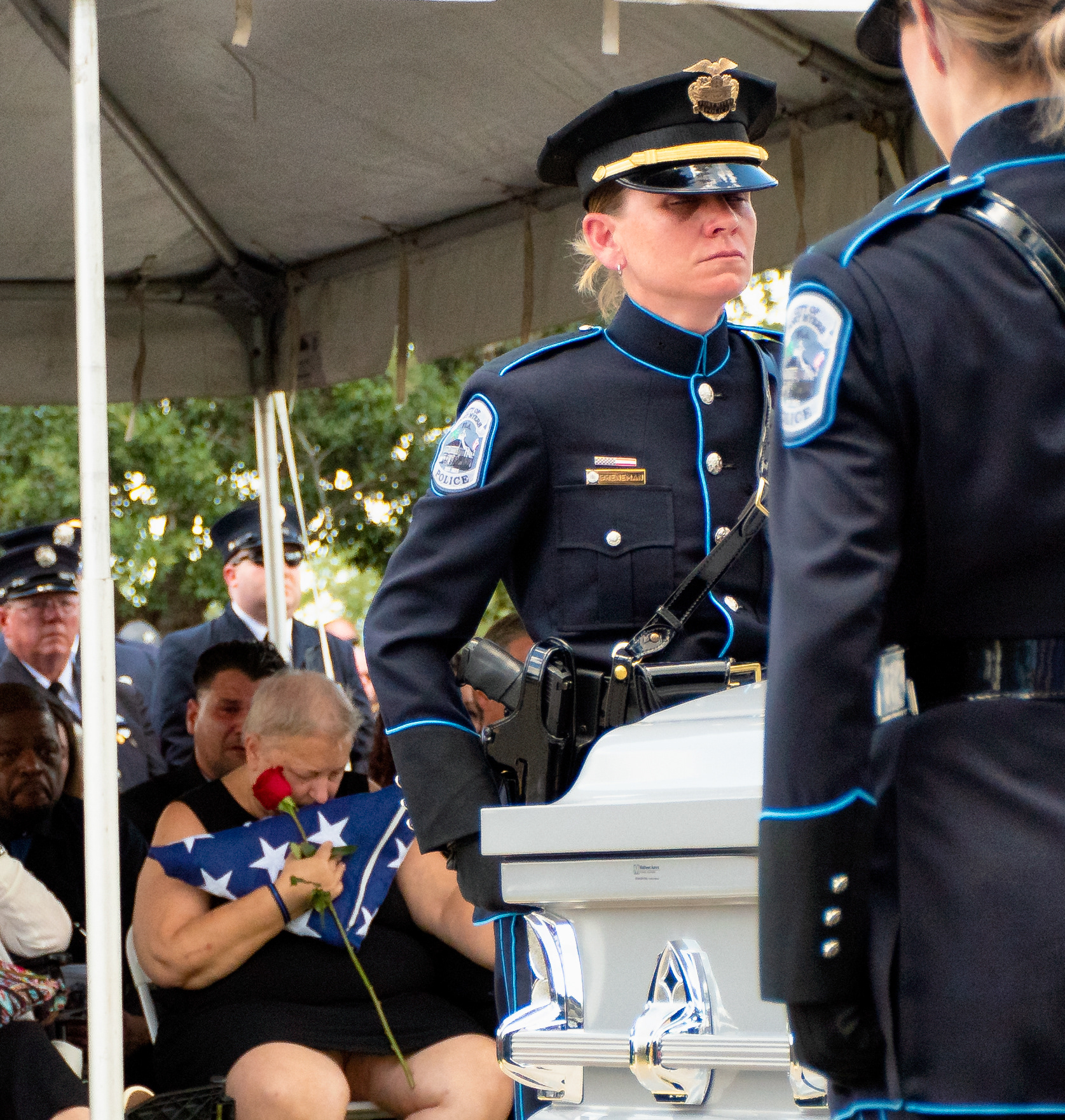 Patricia Miller, the Mother of fallen Ft. Myers Police-Officer Adam Jobbers-Miller, holds an American Flag and a rose, at her sons memorial service, as fellow officers mourn.
