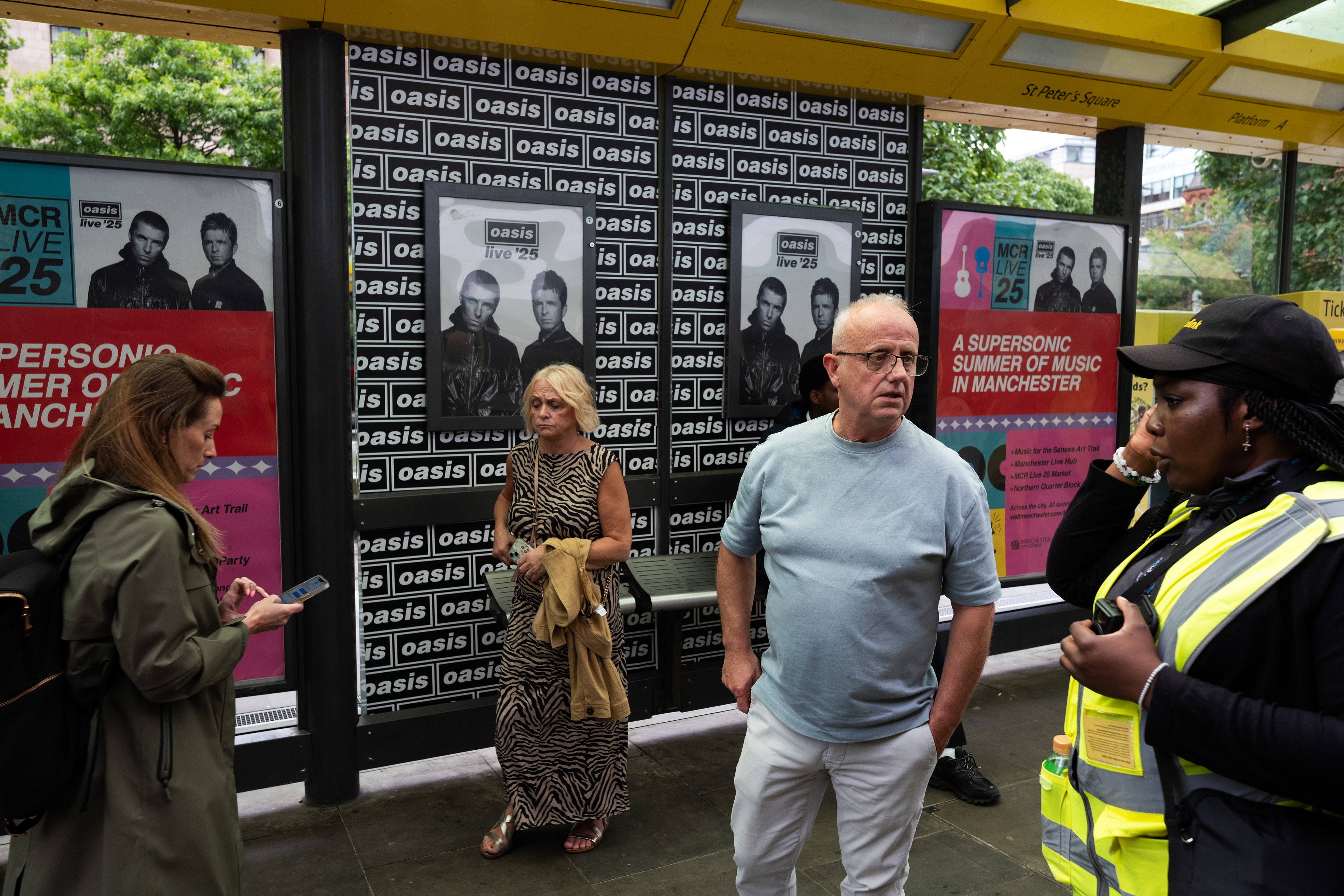Commuters mingle on a St Peters Square tram stop platform - oblivious to the OASIS branding 