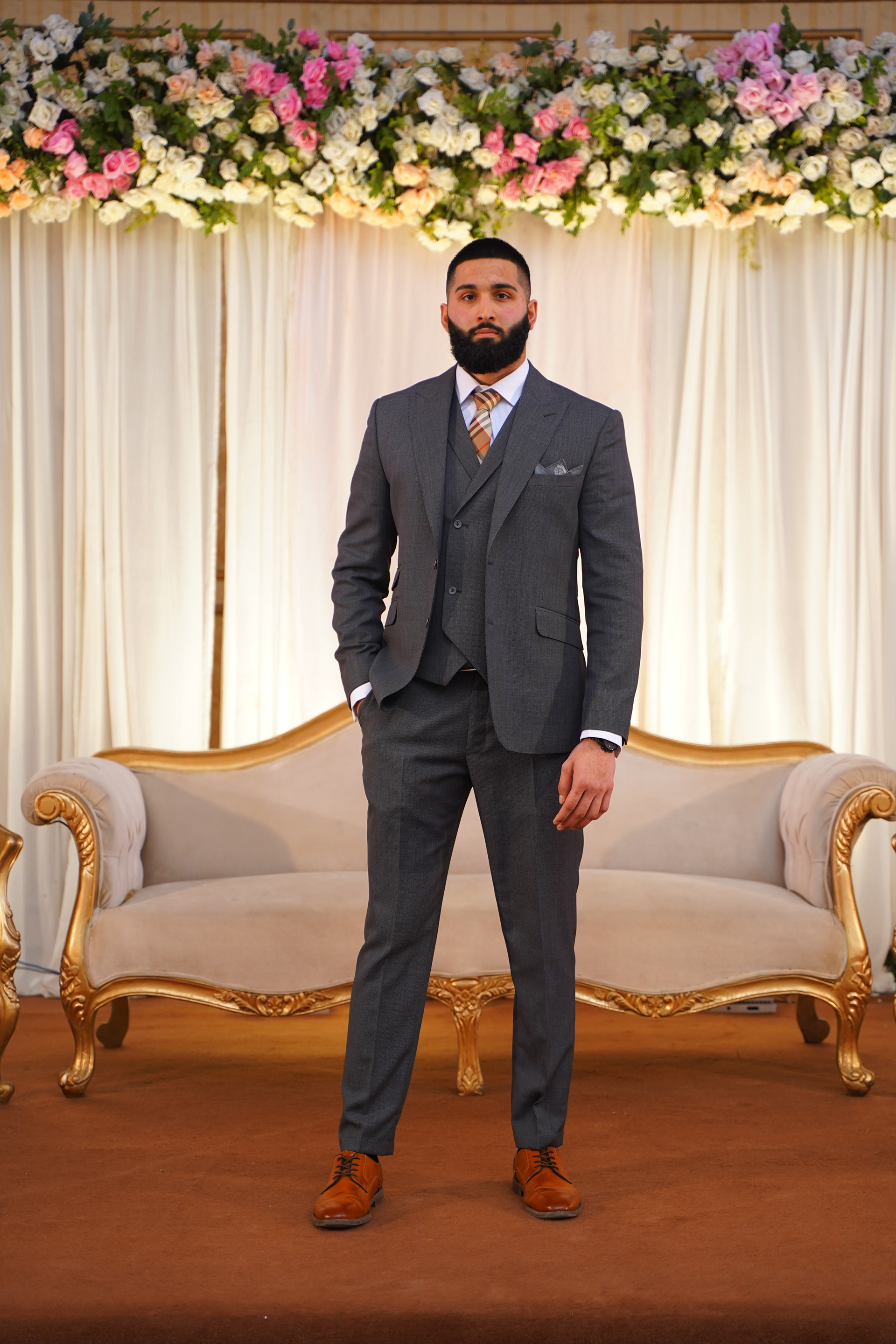 Muhammad Abbasi | Formal Wear | Charcoal three-piece suit with striped tie , hands in pocket