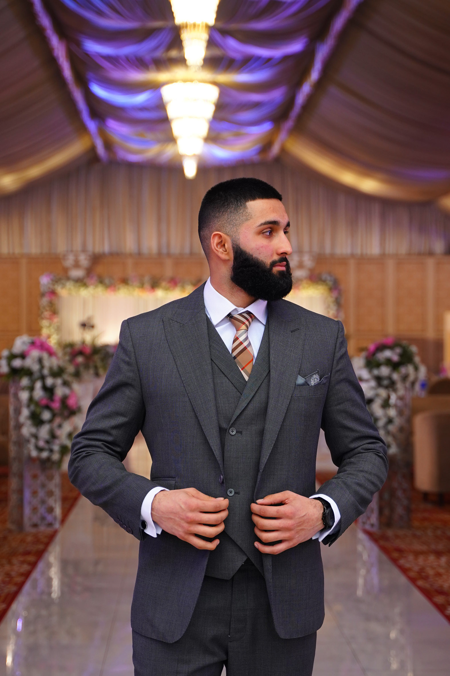 Muhammad Abbasi | Formal Wear | Charcoal three-piece suit with striped tie, looking to the side