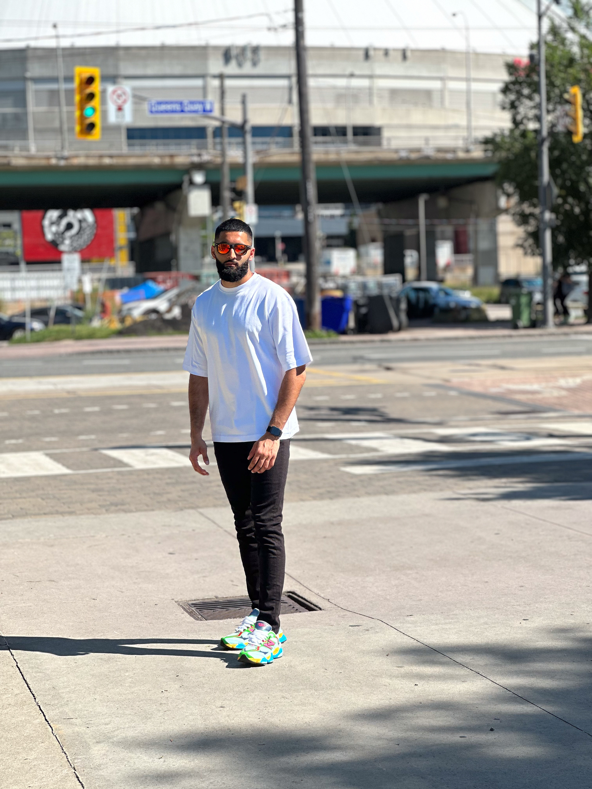 Muhammad Abbasi | Lifestyle | White oversized t-shirt, black jeans, colorful sneakers, standing at intersection in Toronto