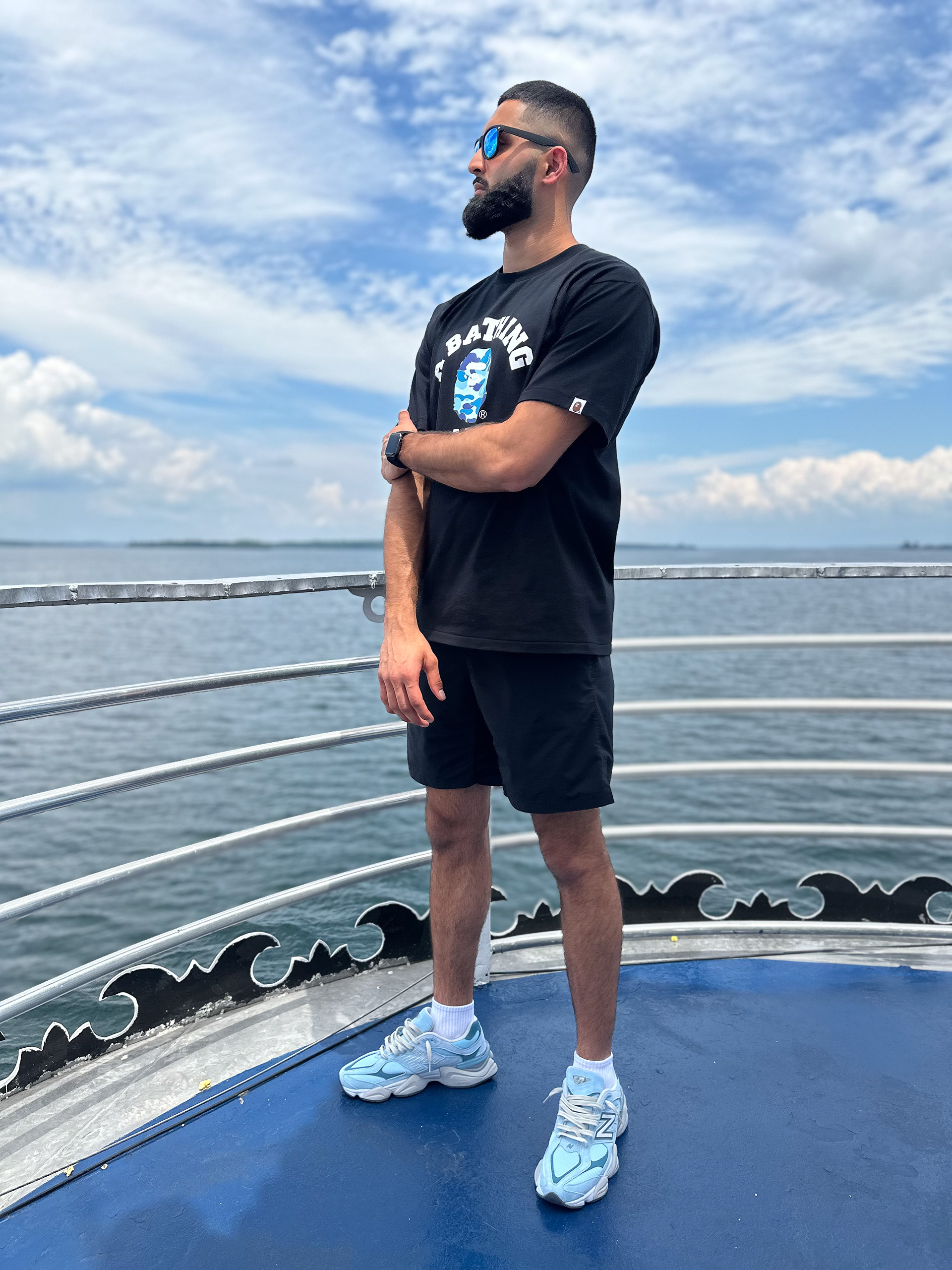 Muhammad Abbasi | Lifestyle | Black graphic t-shirt, black shorts, light blue sneakers, Arms crossed pose on  boat deck over water