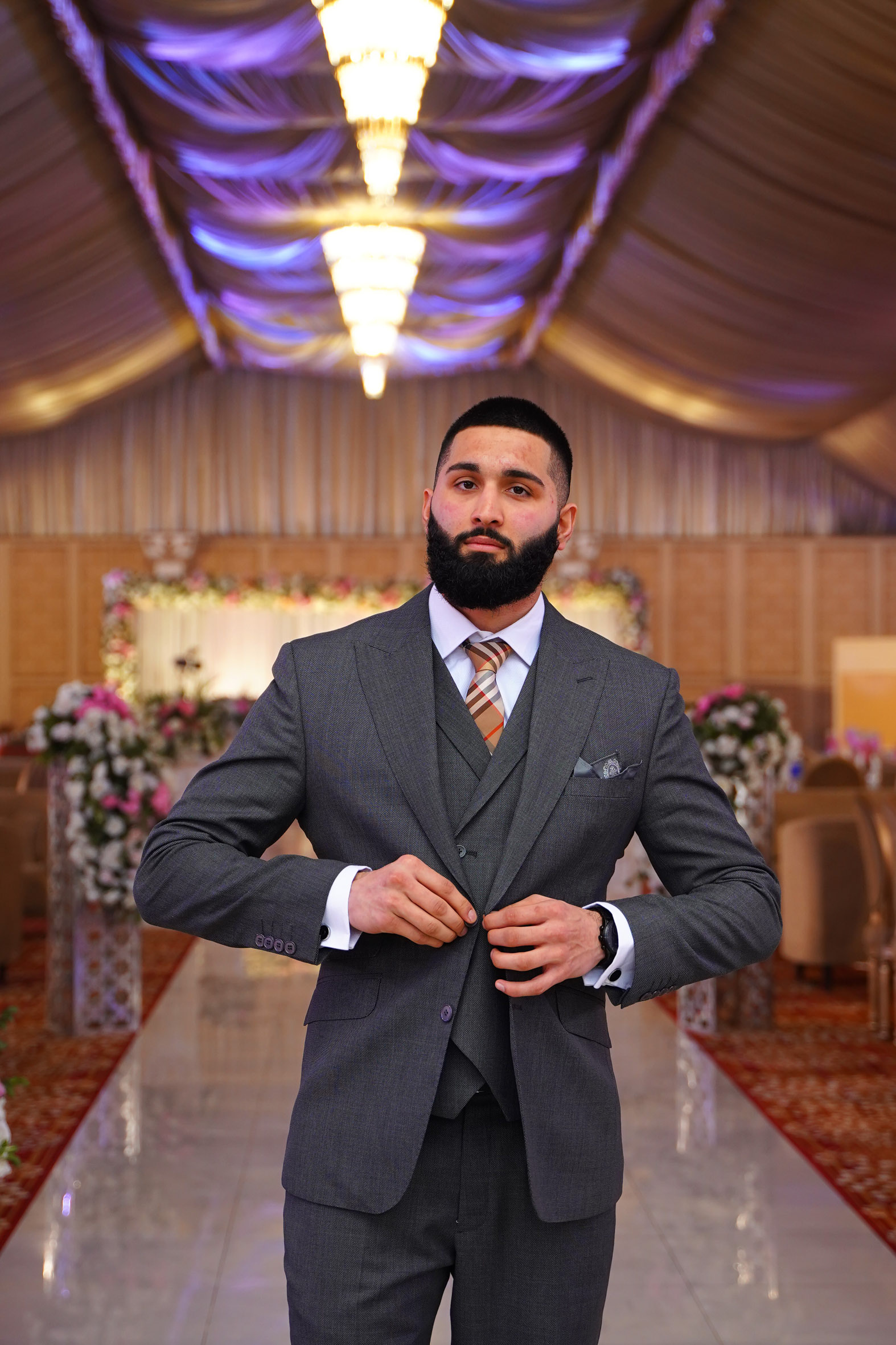 Muhammad Abbasi | Formal Wear | Charcoal three-piece suit with striped tie, fastening jacket button